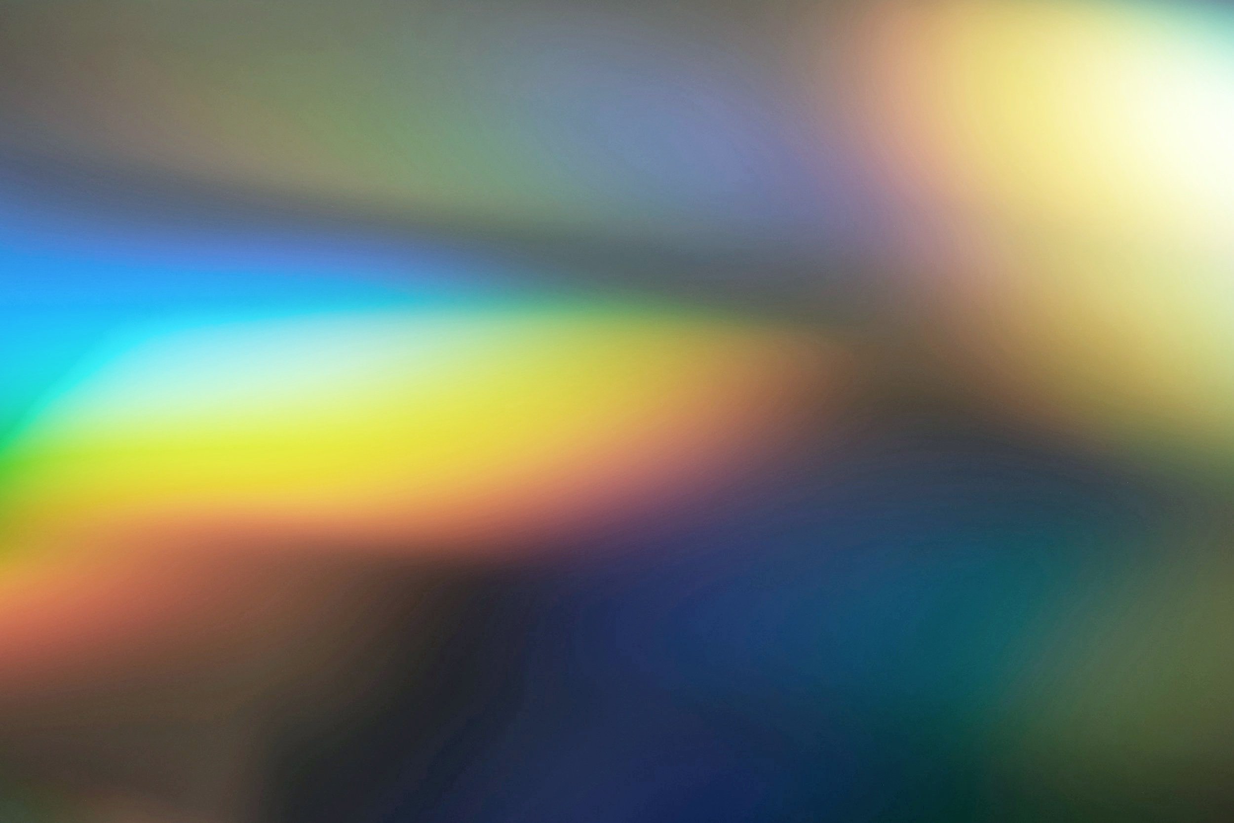 Blurred multicolored abstract background with streaks of yellow, green, blue, and orange.
