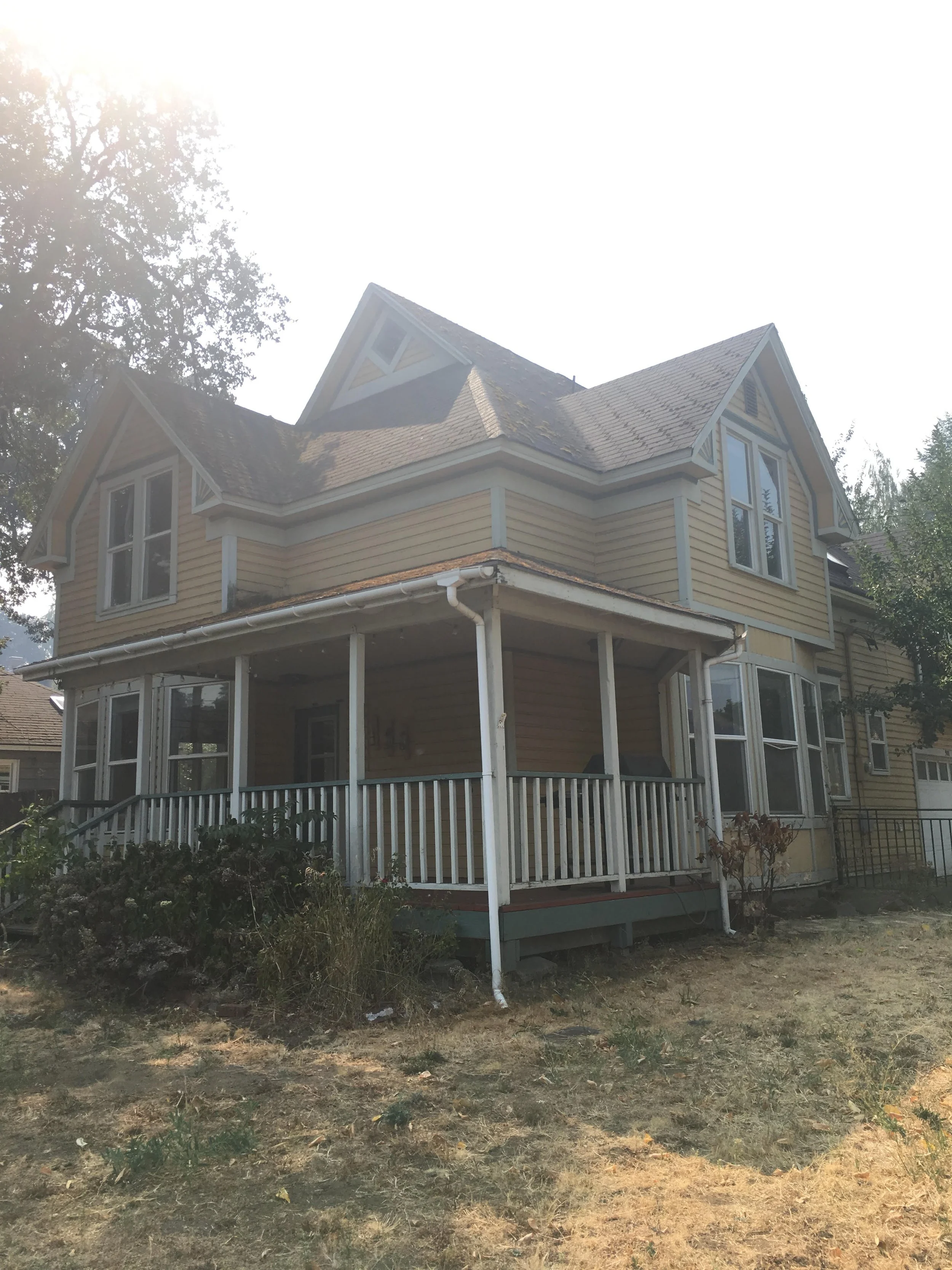 Before picture of Hood River Renovation- yellow house with white railing on the covered front porch