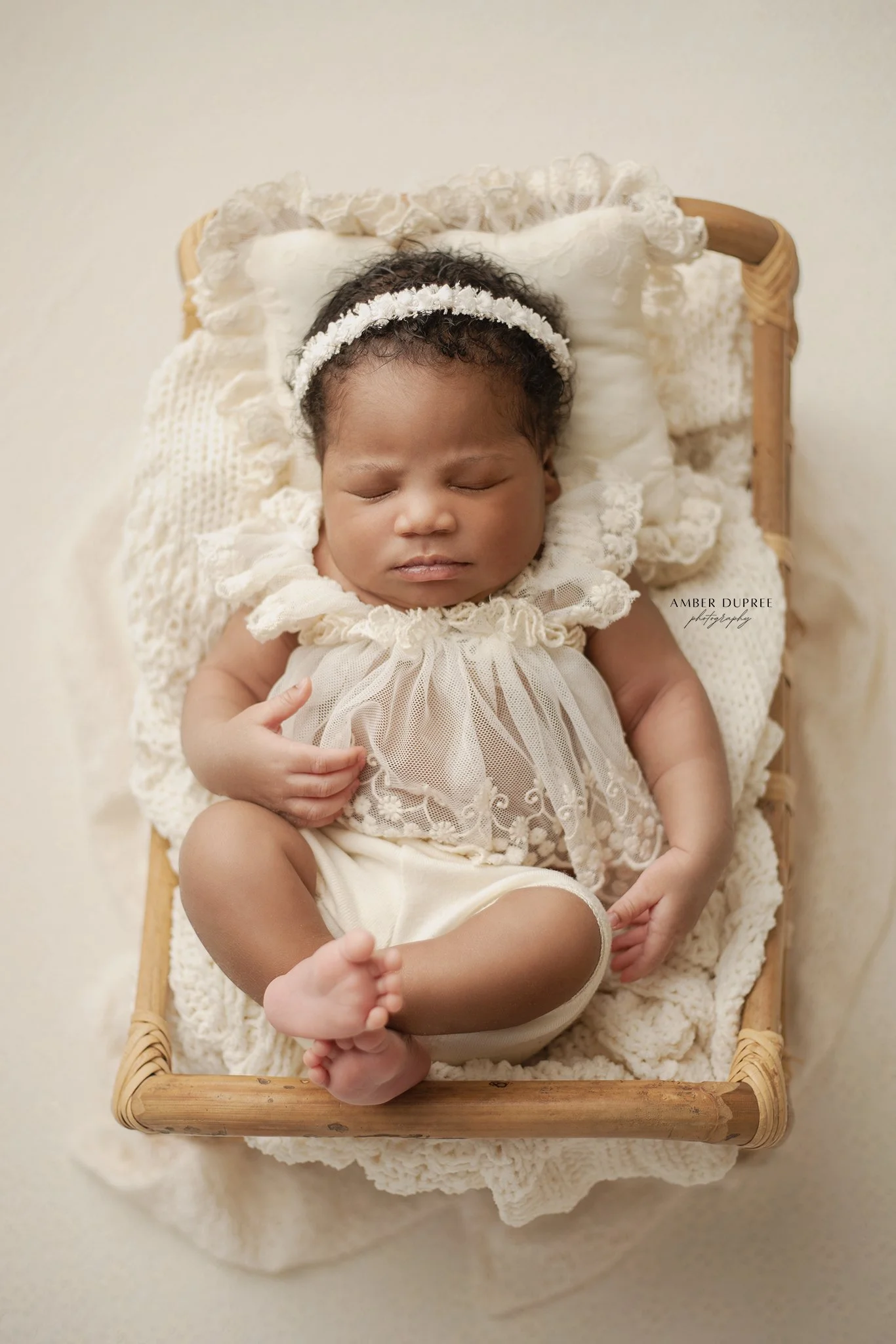 newborn baby girl posed in a wooden basket for her newborn photography session