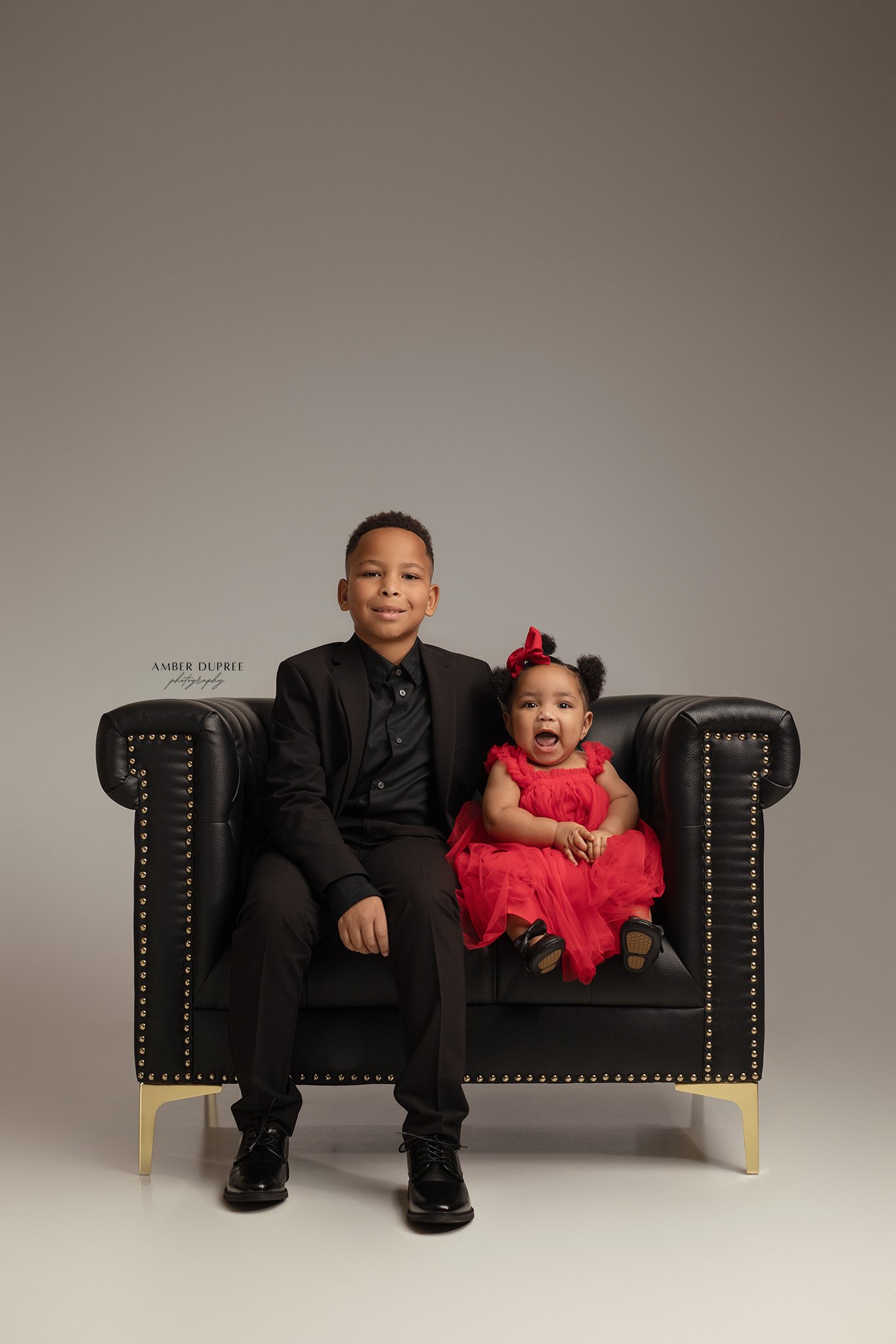 sibling portraits posed in oversized leather chair in nashville, tn photography studio