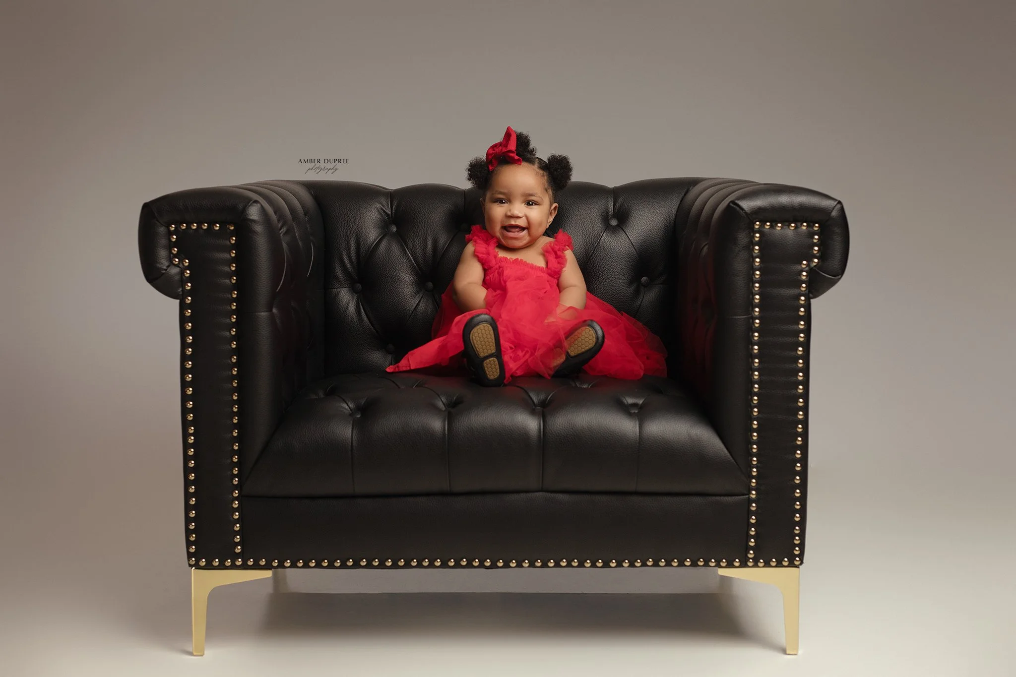 one year old girl portraits posed in oversized leather chair in nashville, tn photography studio