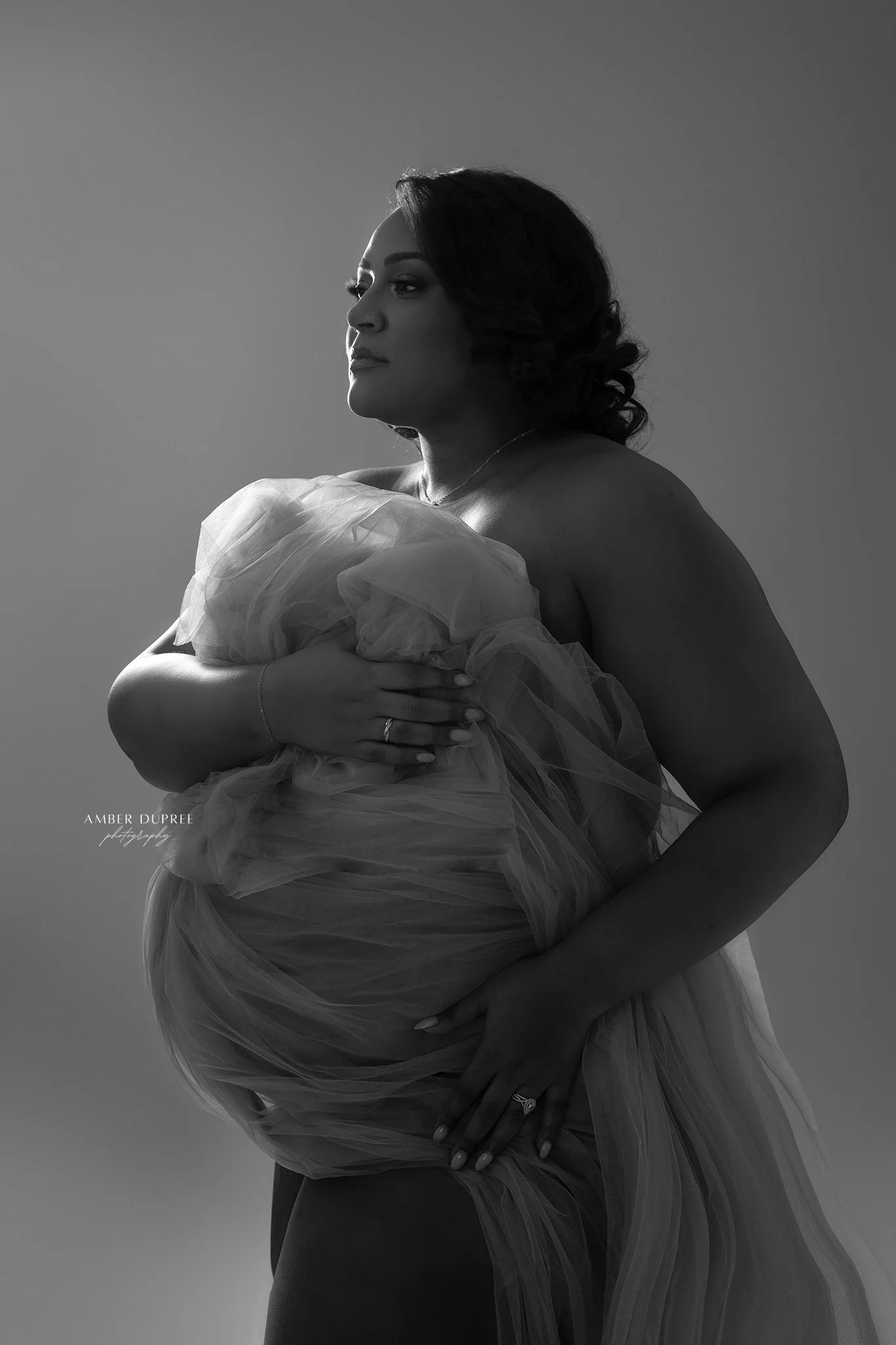 Luxury maternity photography portrait featuring a flowing gown and editorial posing in a Nashville studio.