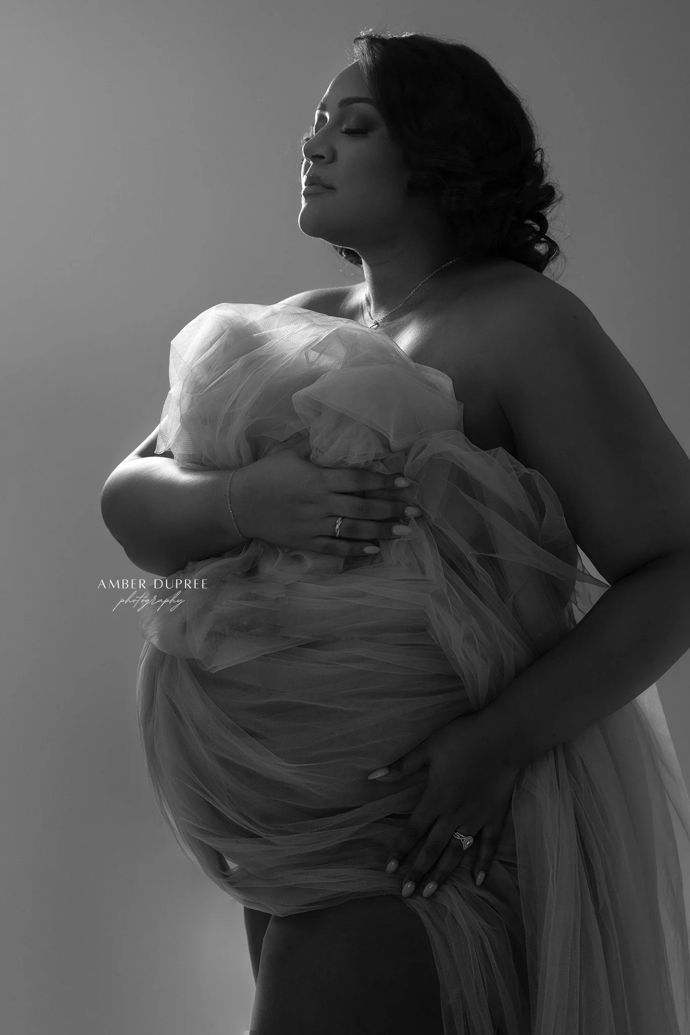 Luxury maternity photography portrait featuring a flowing gown and editorial posing in a Nashville studio.
