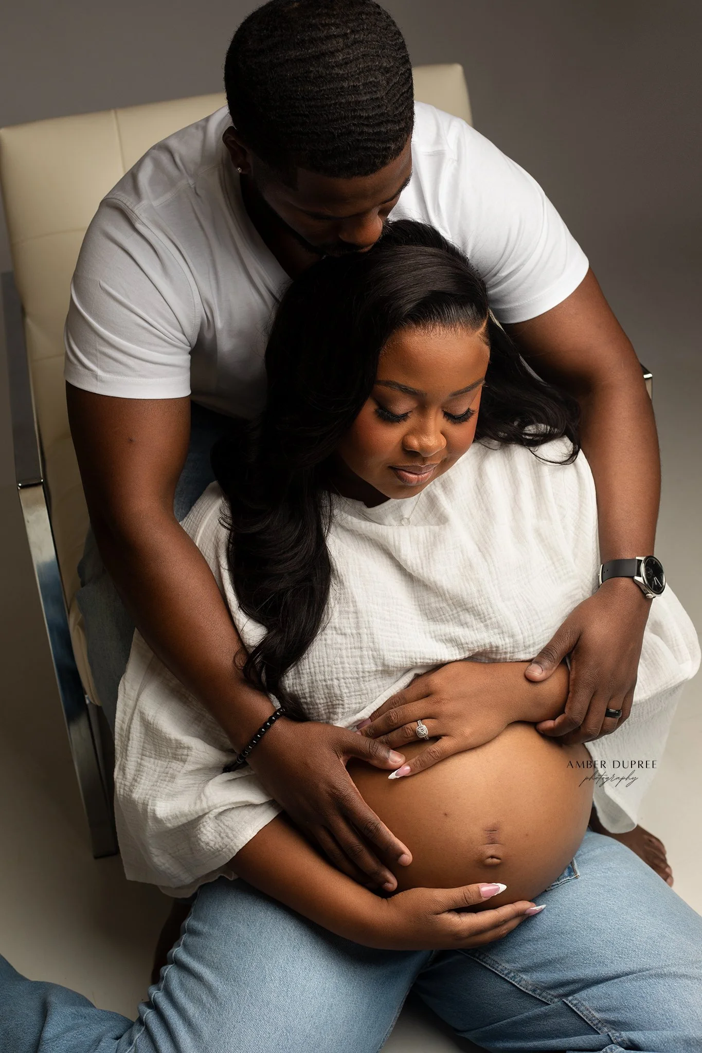 nashville maternity photographer captures husband and wife looking at pregnant belly during maternity session