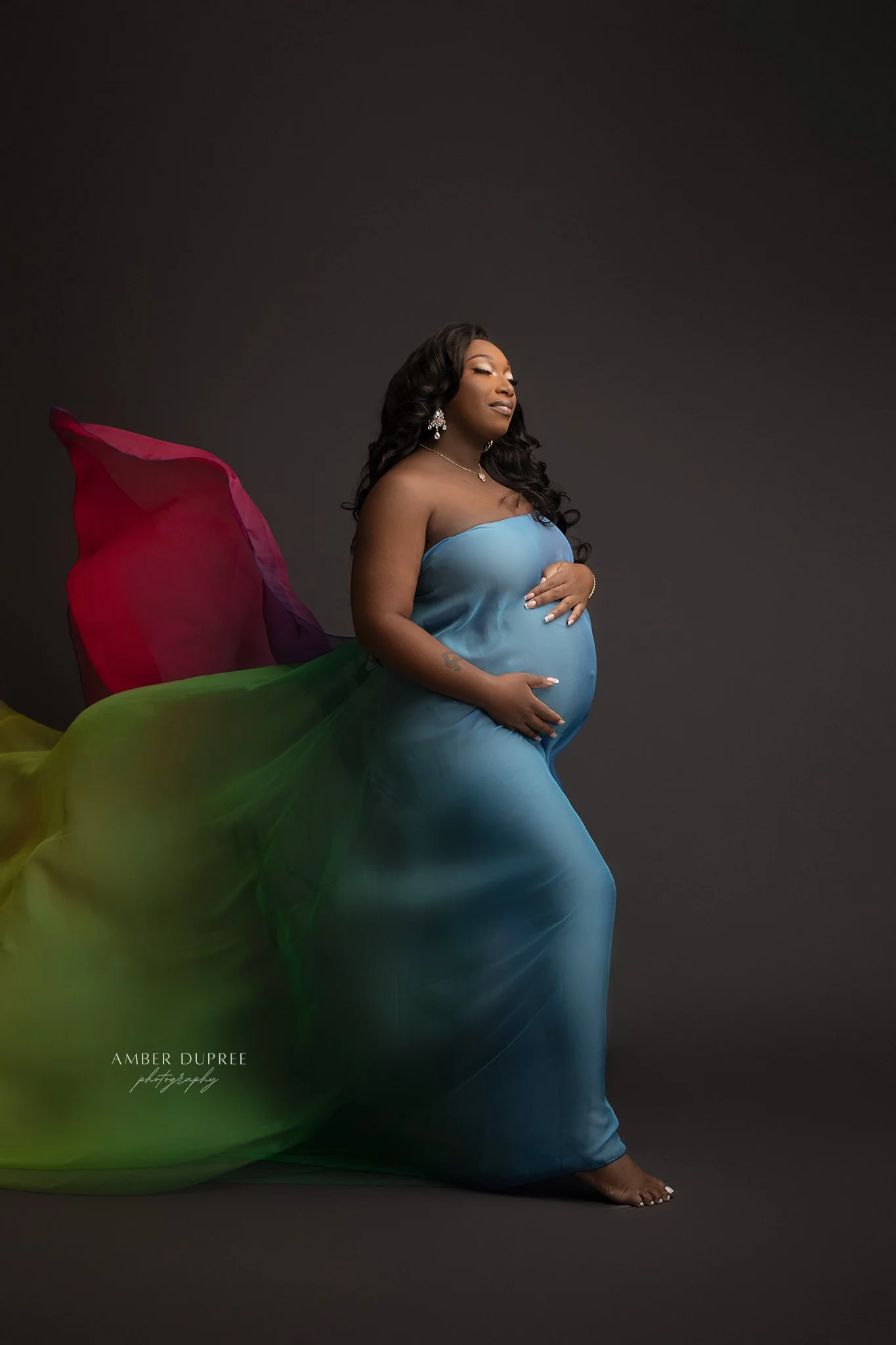 mom with rainbow fabric for rainbow baby maternity photos
