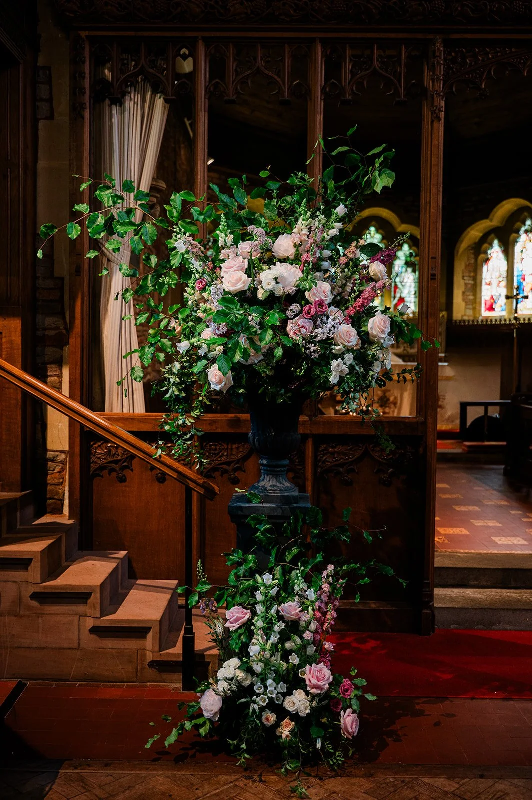 Large floral urn on a stand at a church wedding