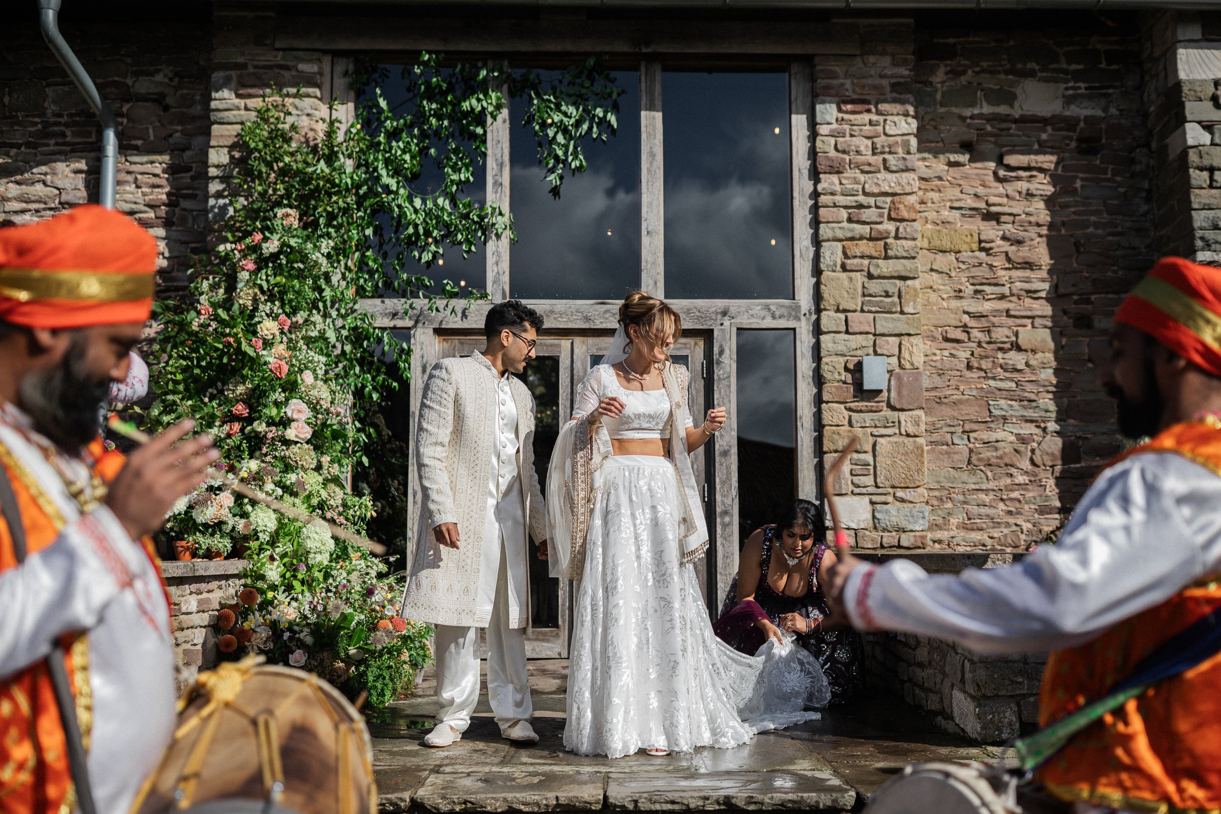 Bride and groom in front of a large floral installation at a wedding entrance