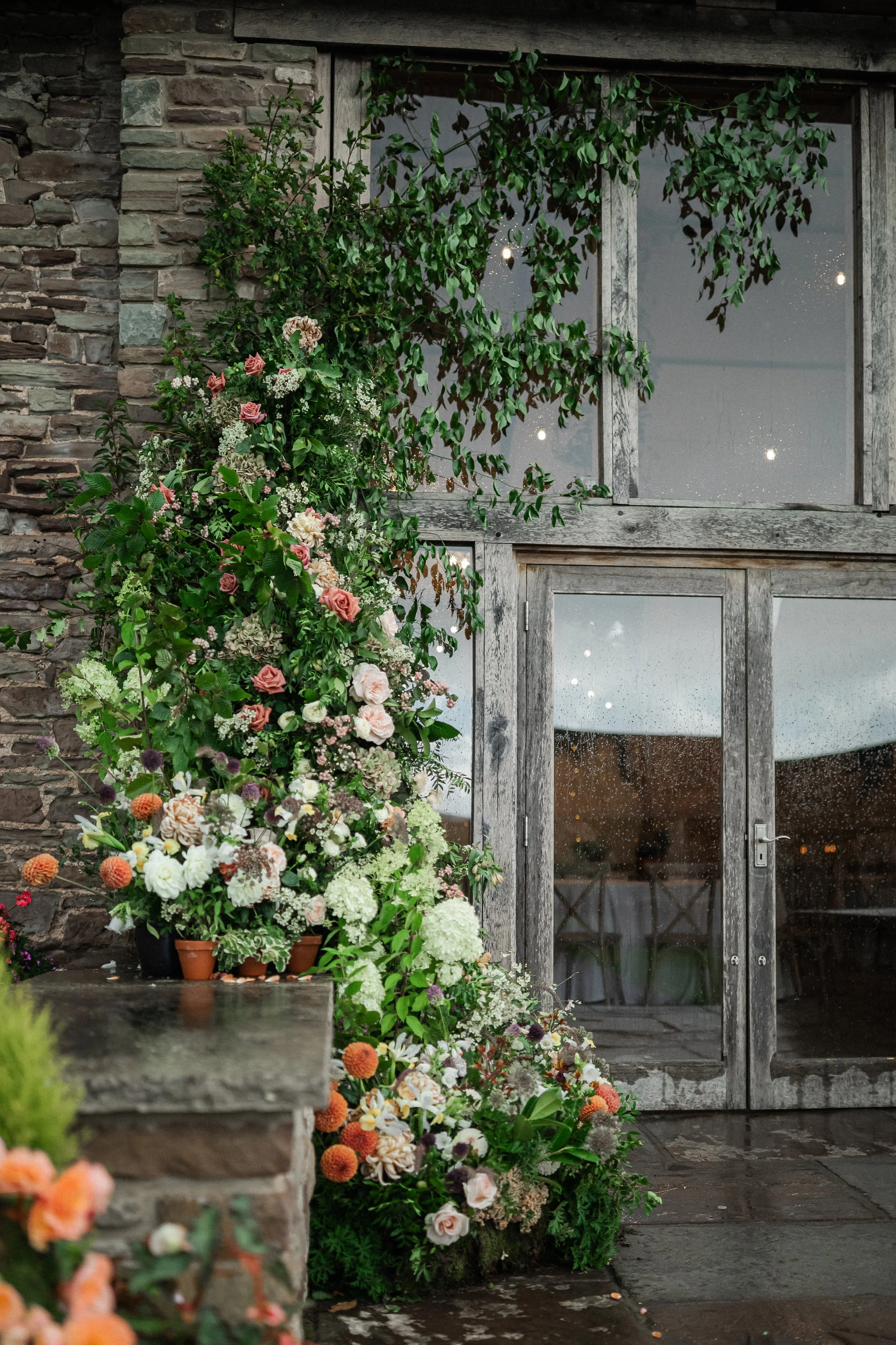 Large colourful flower installation at a wedding entrance at Naas Court Farm Wedding Barn, Lydney, Forest of Dean