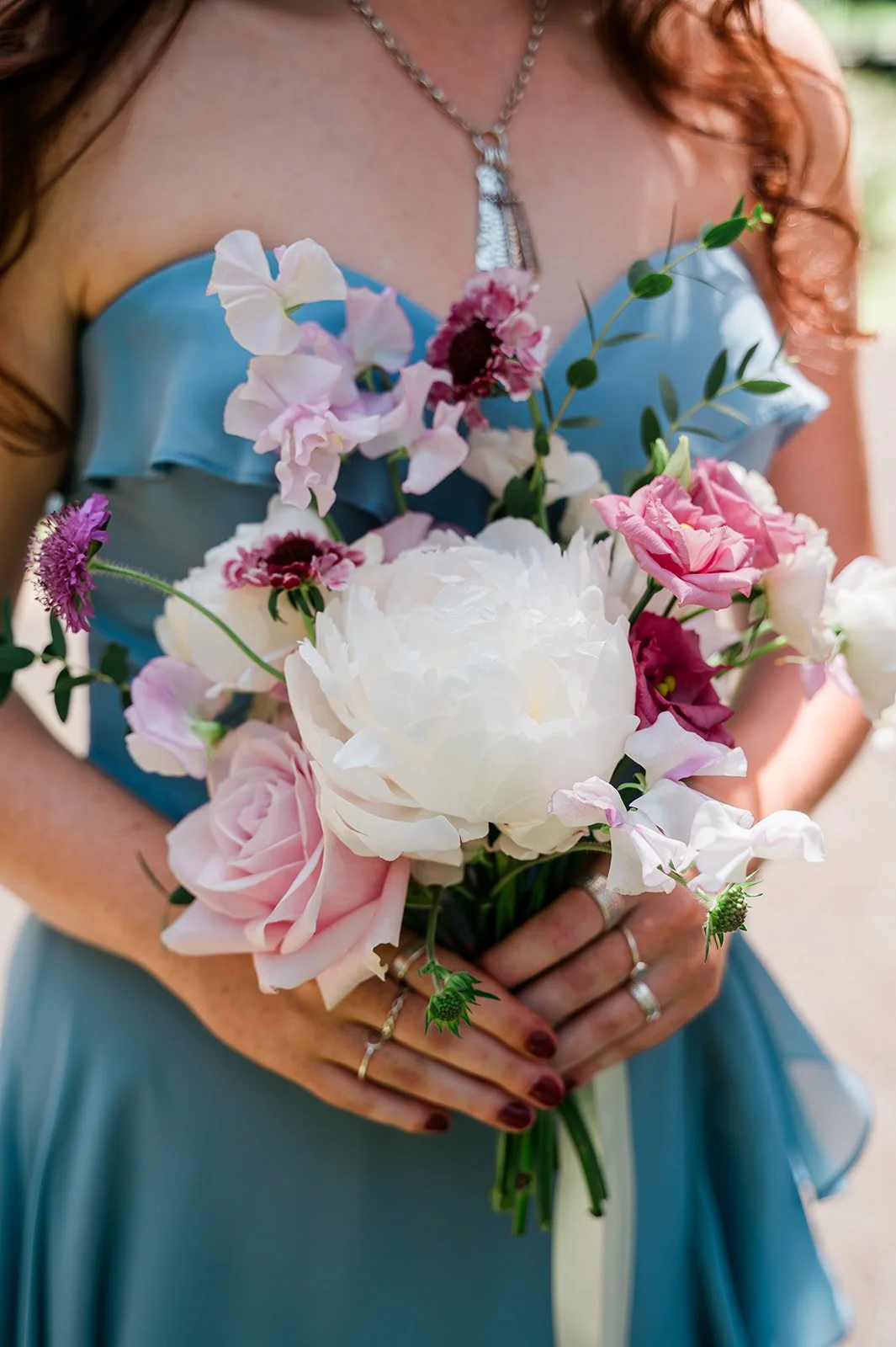 Girl in a blue dress holding a pretty pink and white bridesmaid bouquet