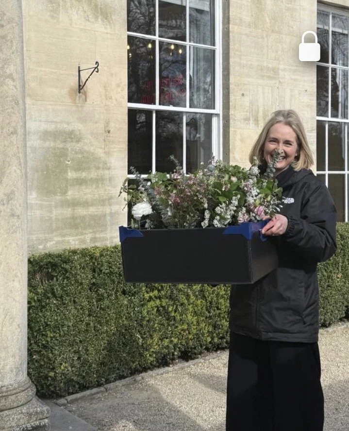 Somerset wedding florist carrying a crate of spring flowers