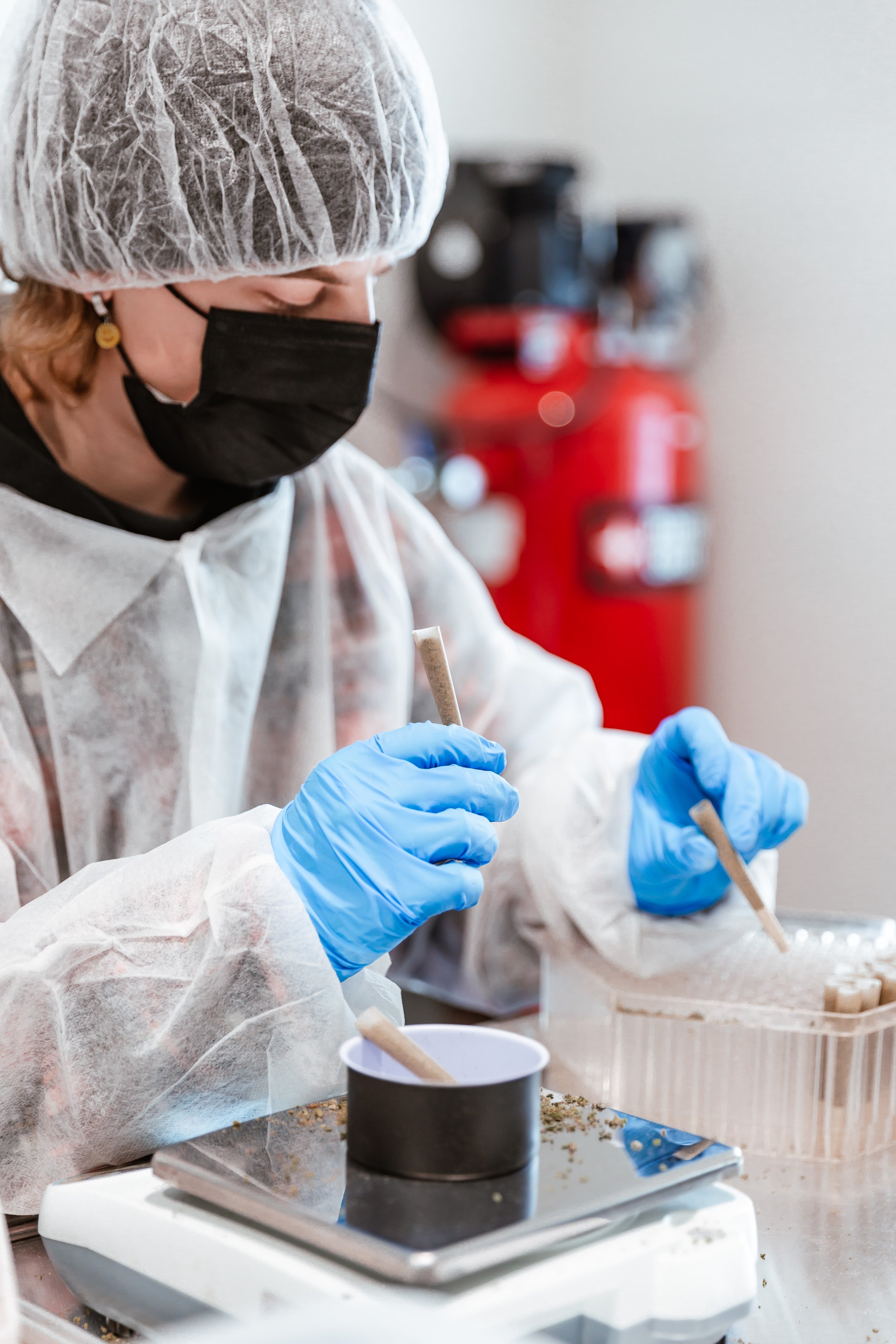 Person in protective clothing and gloves working with small tubes in a lab setting.