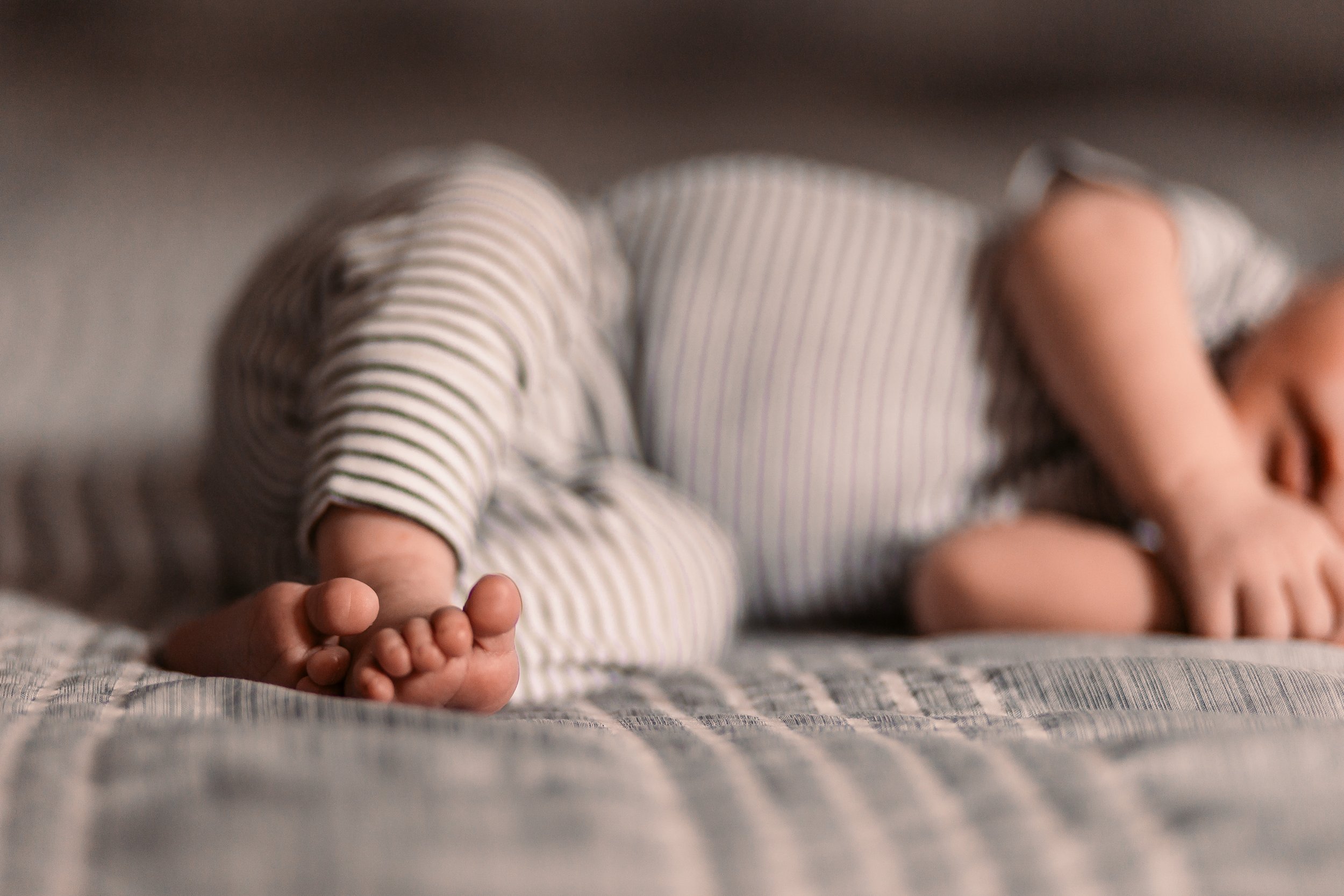 Close-up of a baby's bare feet against a striped fabric background.