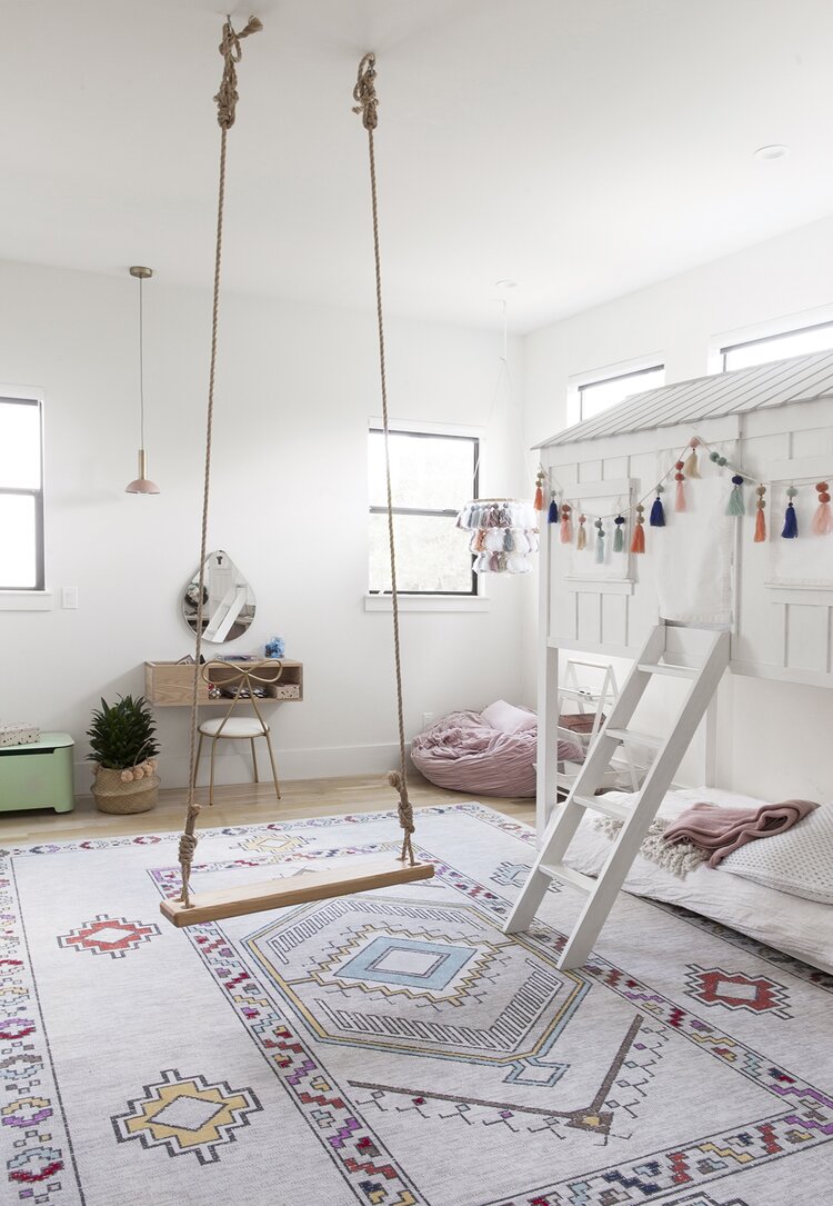 A wooden swing hung from the ceiling in a girls room