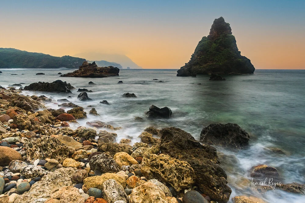 Rocky coastline with large sea stacks and a pebble beach at sunset