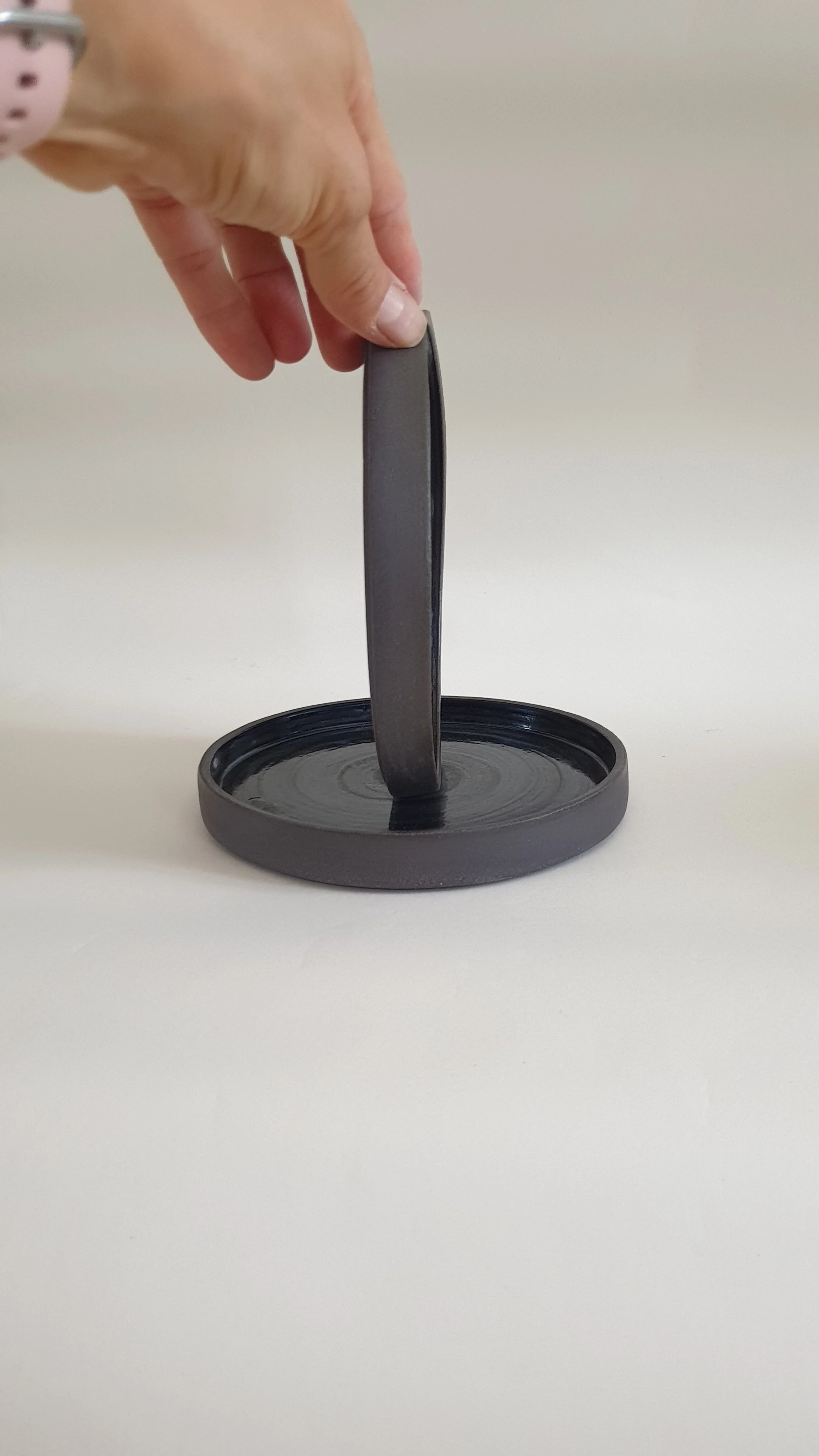 Mano che tiene un anello di metallo verticale sopra una base rotonda.