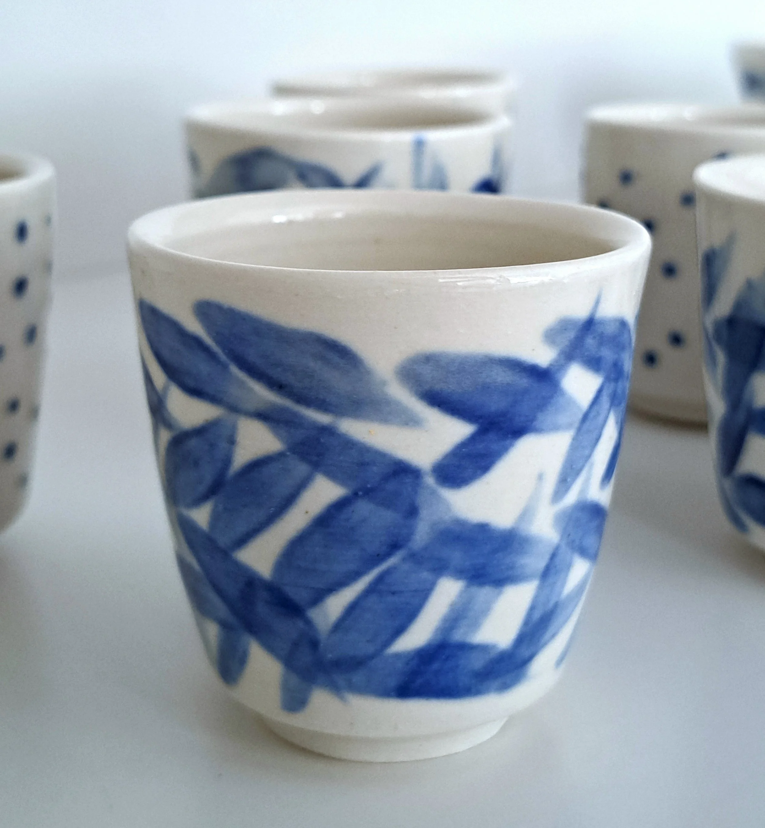 Tazzine di ceramica bianche decorate con disegni blu, alcune piene di liquido, altre vuote.