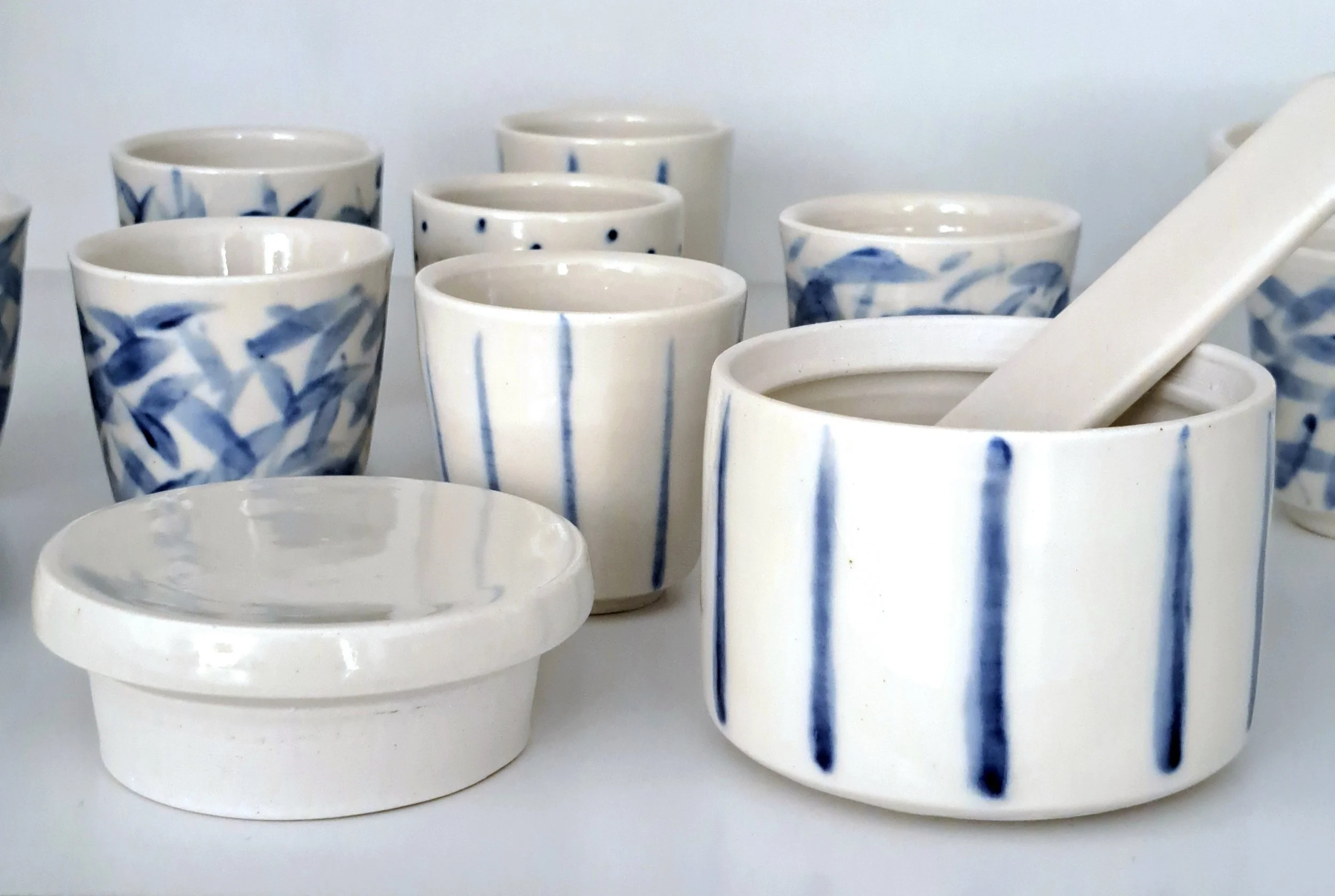 Tazze di ceramica bianche decorate con motivi blu, alcune con cucchiaini all'interno.