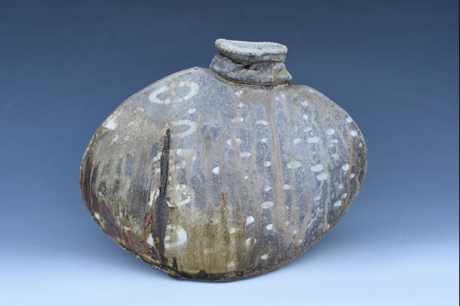 This pouch vase has my porcelain inlaid into my red clay, and it was wood fired at Solano Community College.

That dark stripe on the side? Total accident. It&rsquo;s where this piece got stuck to another one in the kiln. Could have been bad. Instead