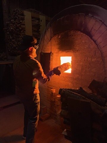 Stoking wood in the firebox of an anagama kiln