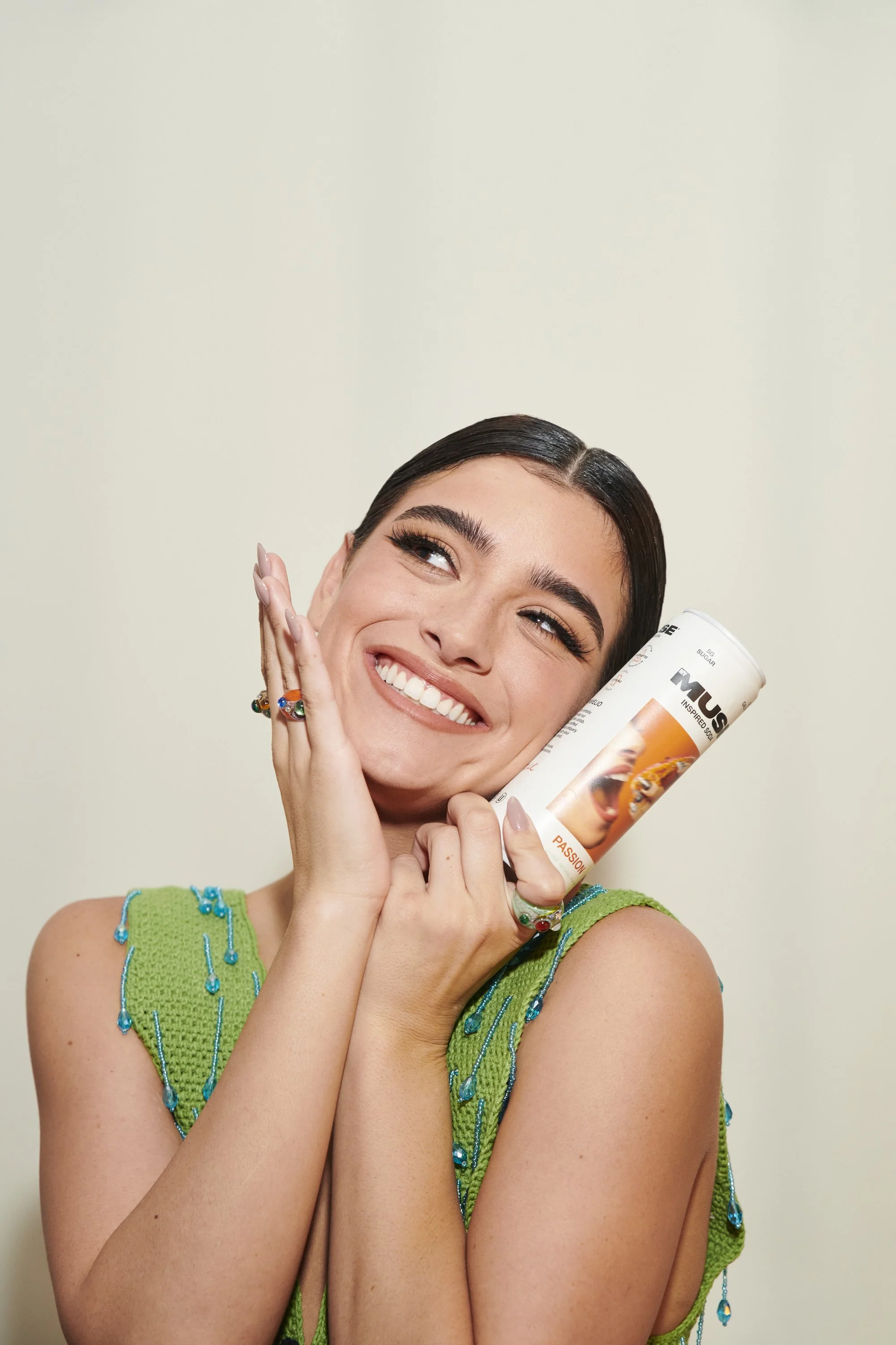 A young woman smiles holding an orange soda, shot by commercial photographer Linnea Bullion.