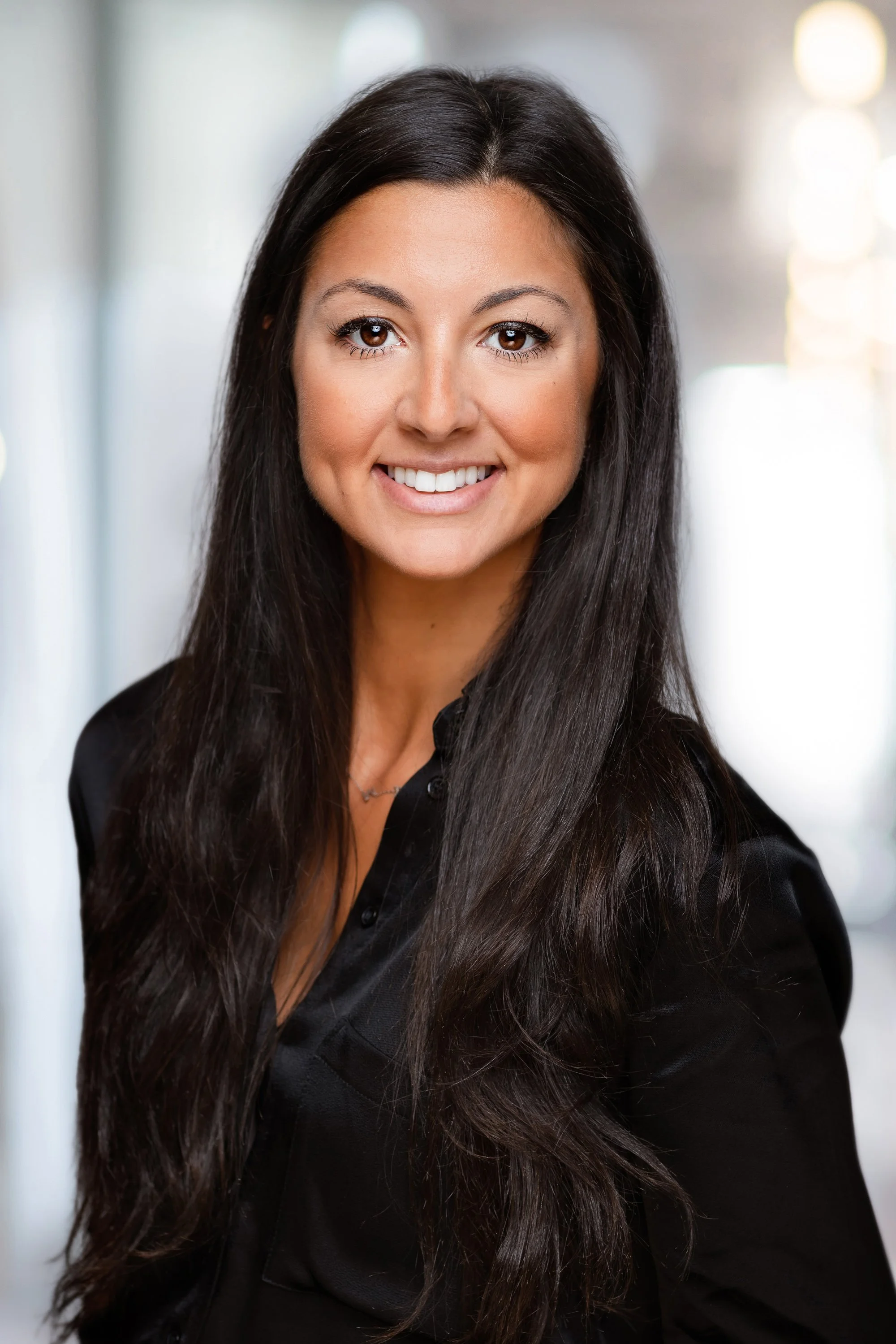 Executive headshot of a woman in a black shirt against a softly blurred office background