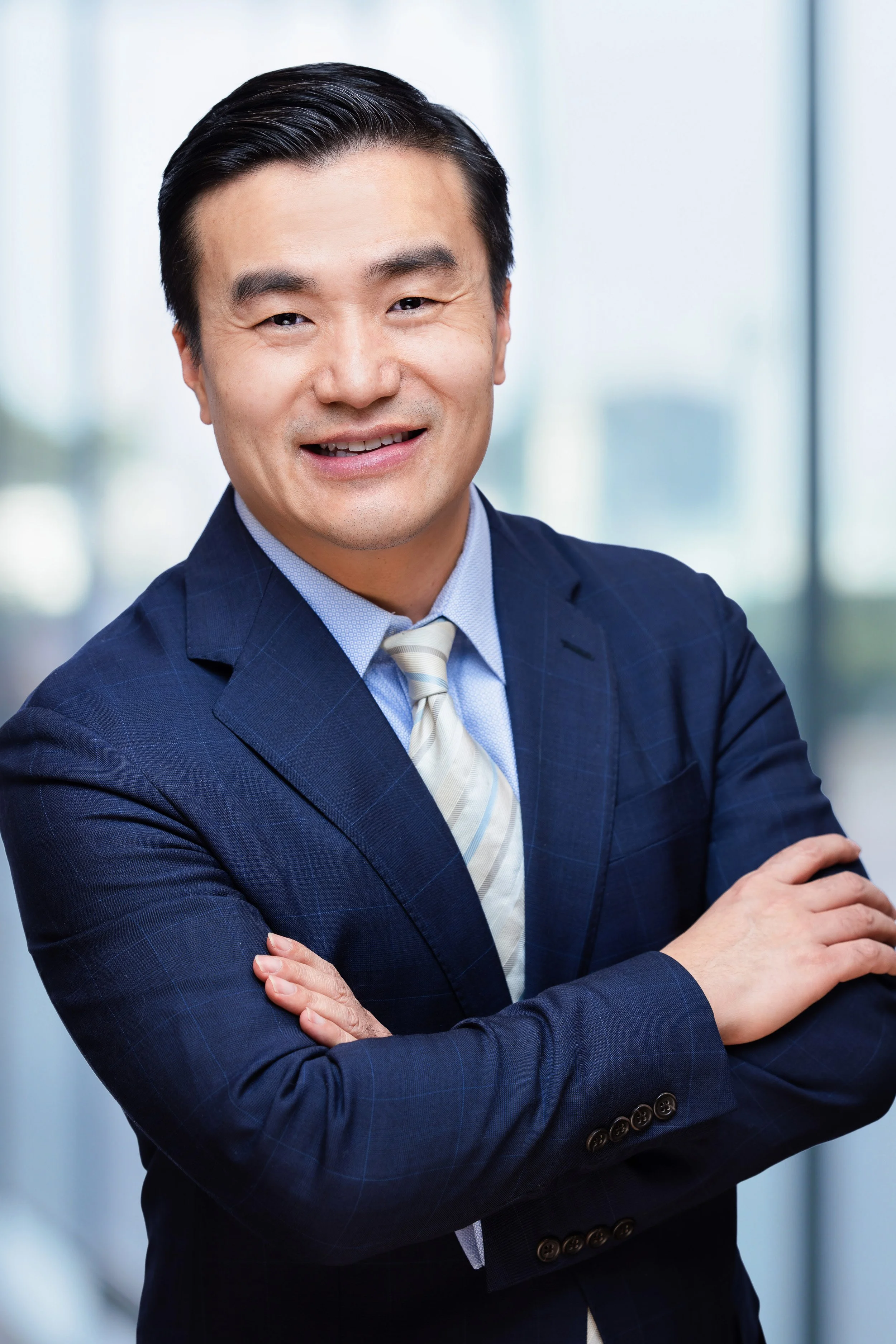 business headshot of a man smiling and folding his arms looking at the camera
