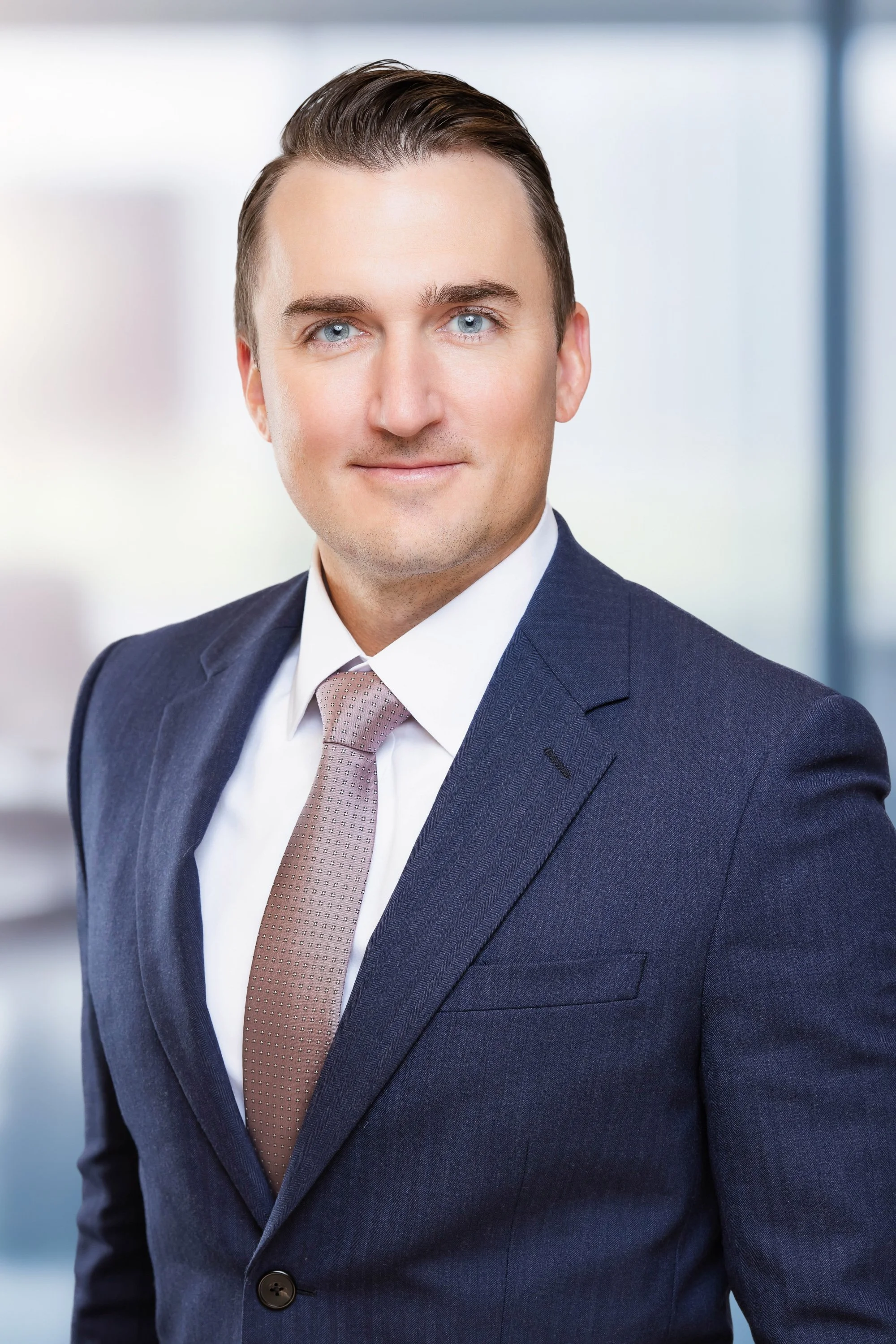 Executive headshot of a man in a navy suit against a softly blurred office background