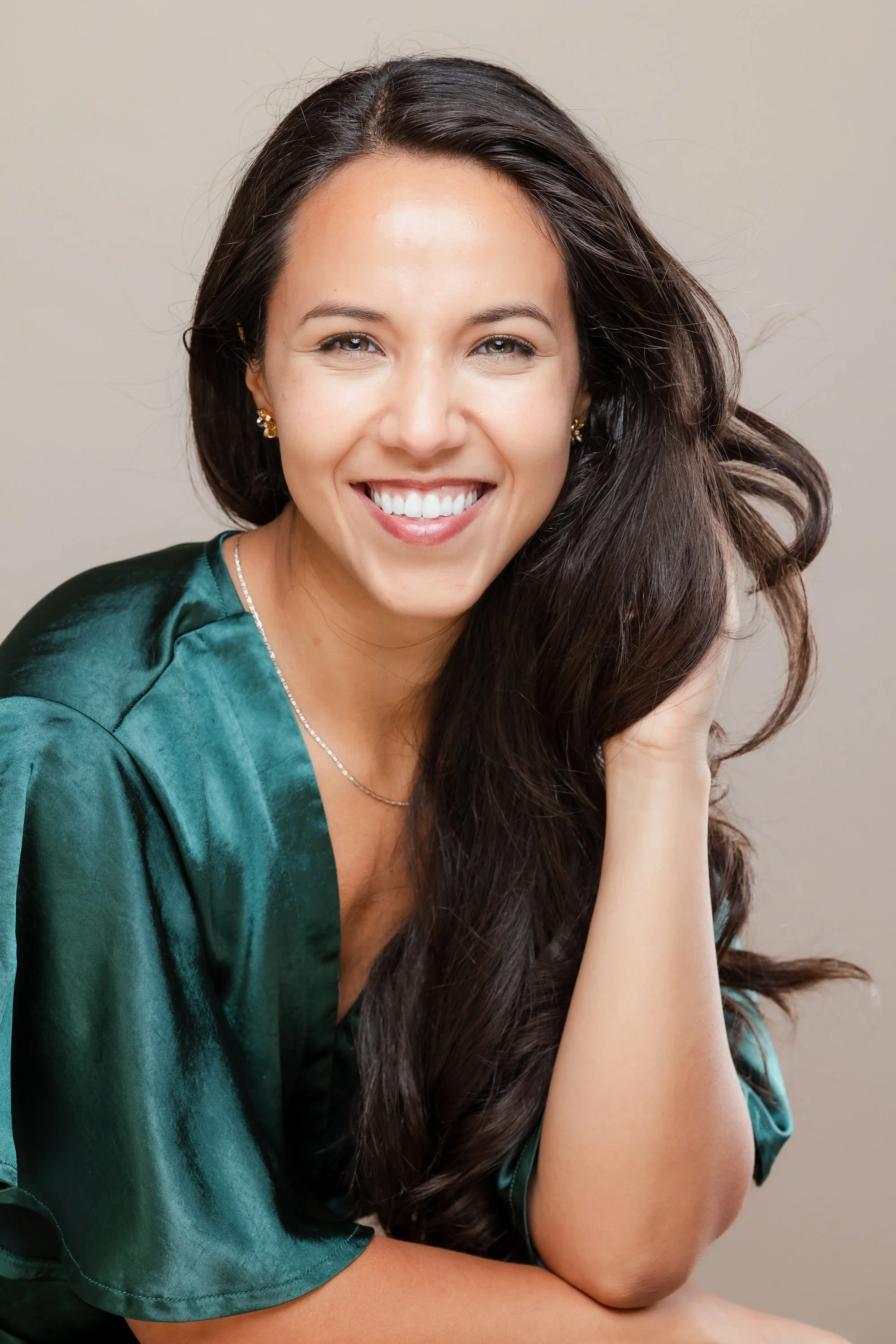Executive headshot of a woman in a green top against a tan background
