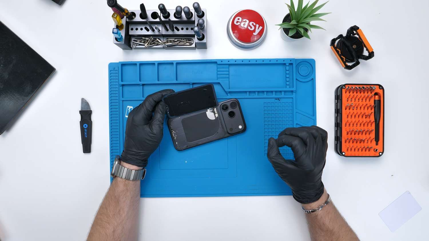 Lifting the back glass from the black iPhone during the teardown.