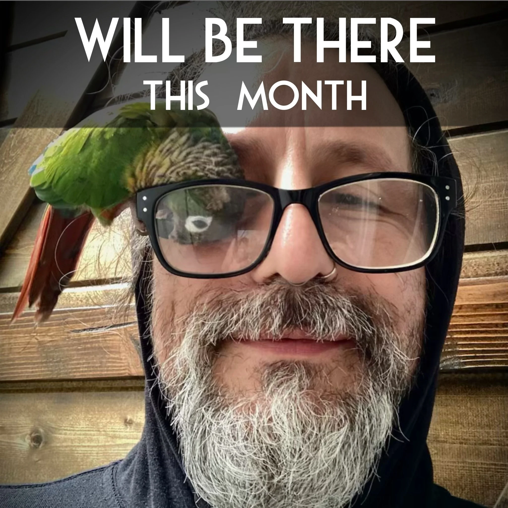 A person wearing glasses, with a lot of gray and white beard and hair, lies on a wooden surface with a parakeet perched on their head. Overlay text reads, 'WILL BE THERE THIS MONTH.'
