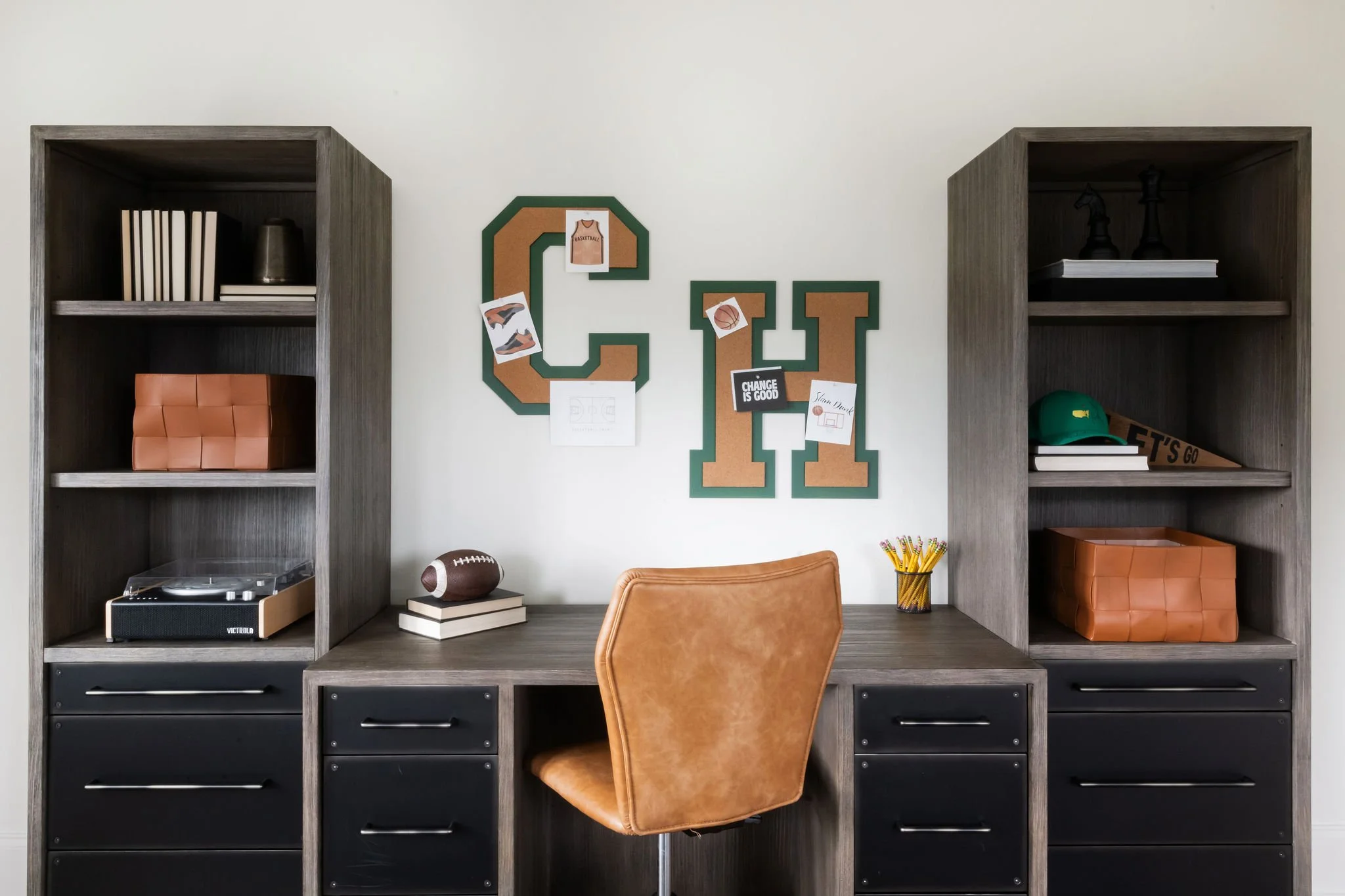 Home office with desk, brown leather chair, bookshelves, and sports-themed decorations on the wall.