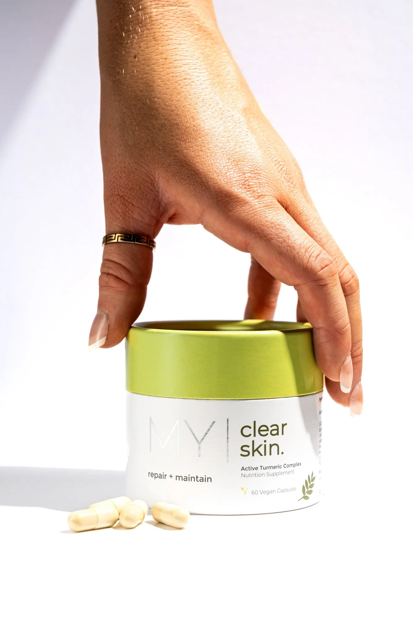Model's hand grabbing container of MY Visage Clearn Skin on a white background product photo
