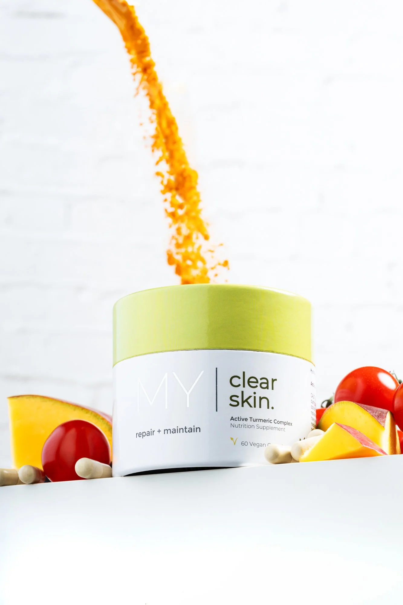 Hero product photo of My Visage Clear Skin surrounded by key ingredients tumeric, mango, tomatoes