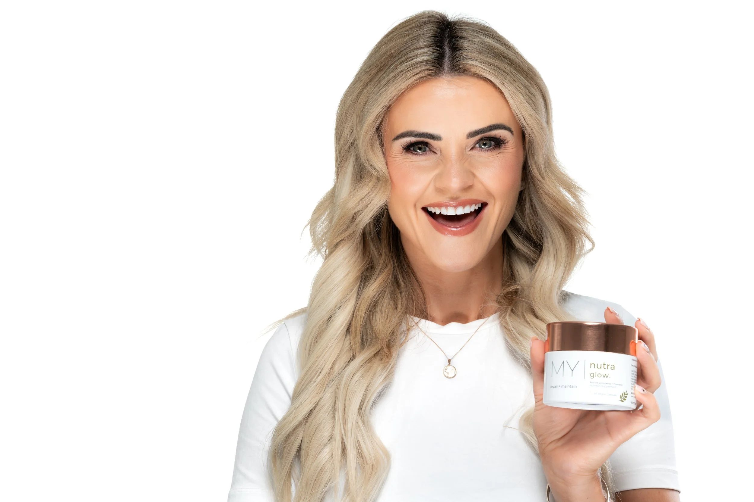 Missy Glow Rachel Rice holding My Visage Nutra Glow supplement smiling on white studio background