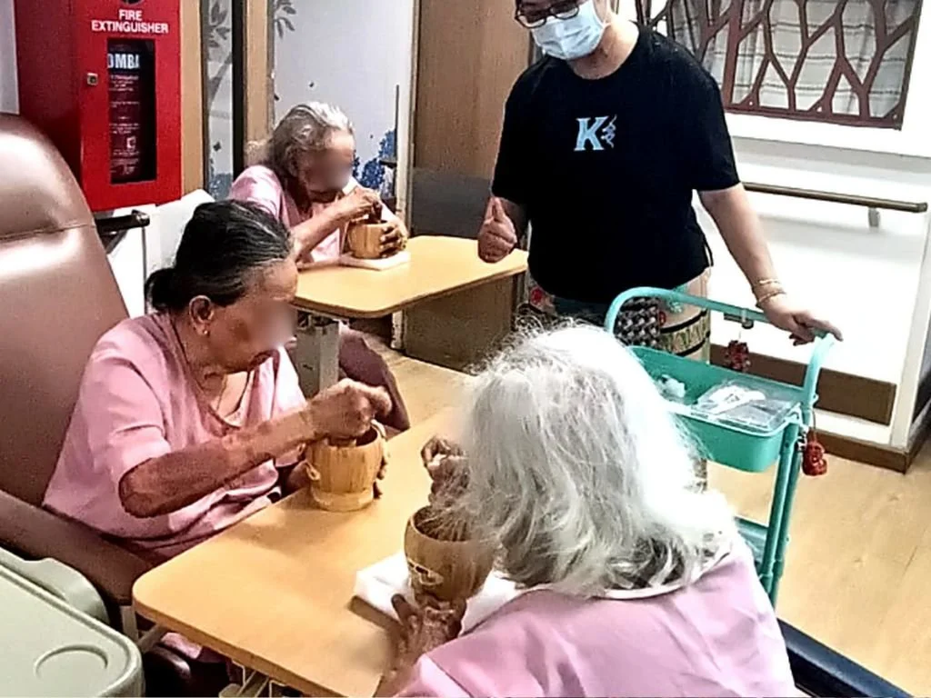 Senior facilitator engaging nursing home residents in a small group activity at Open Village