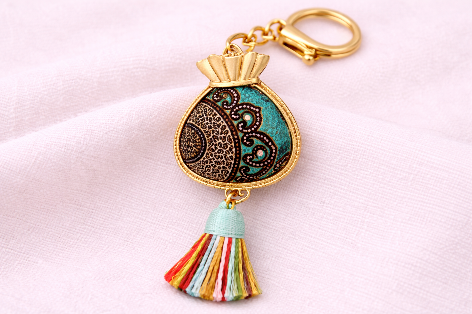 Batik-inspired round tassel keychain with gold details and colourful tassel
