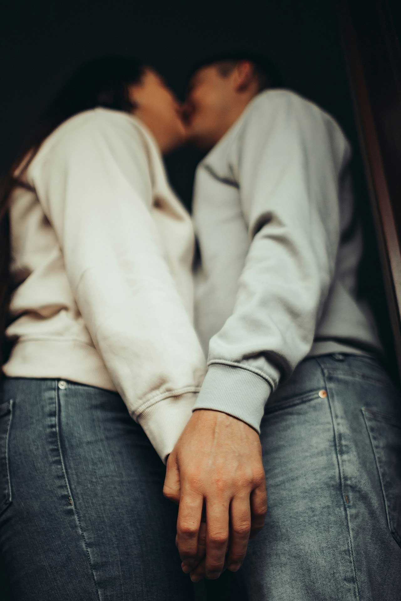 A couple standing close together, facing each other, holding hands.