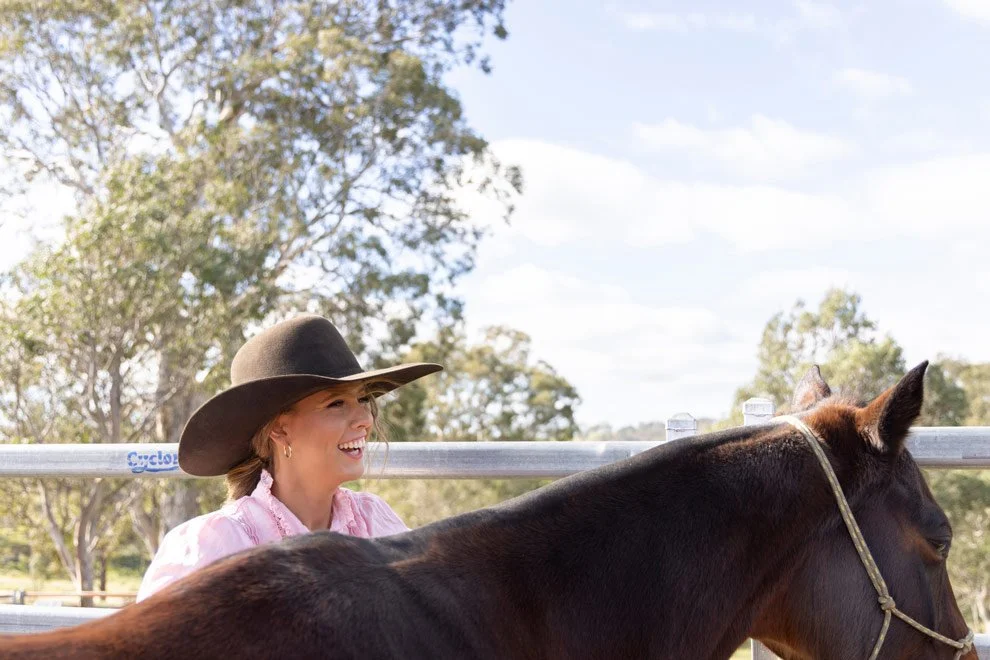 Personal brand photography, Sophie of Reins to Resilience smiling with horse in yards, Sapphire Coast NSW