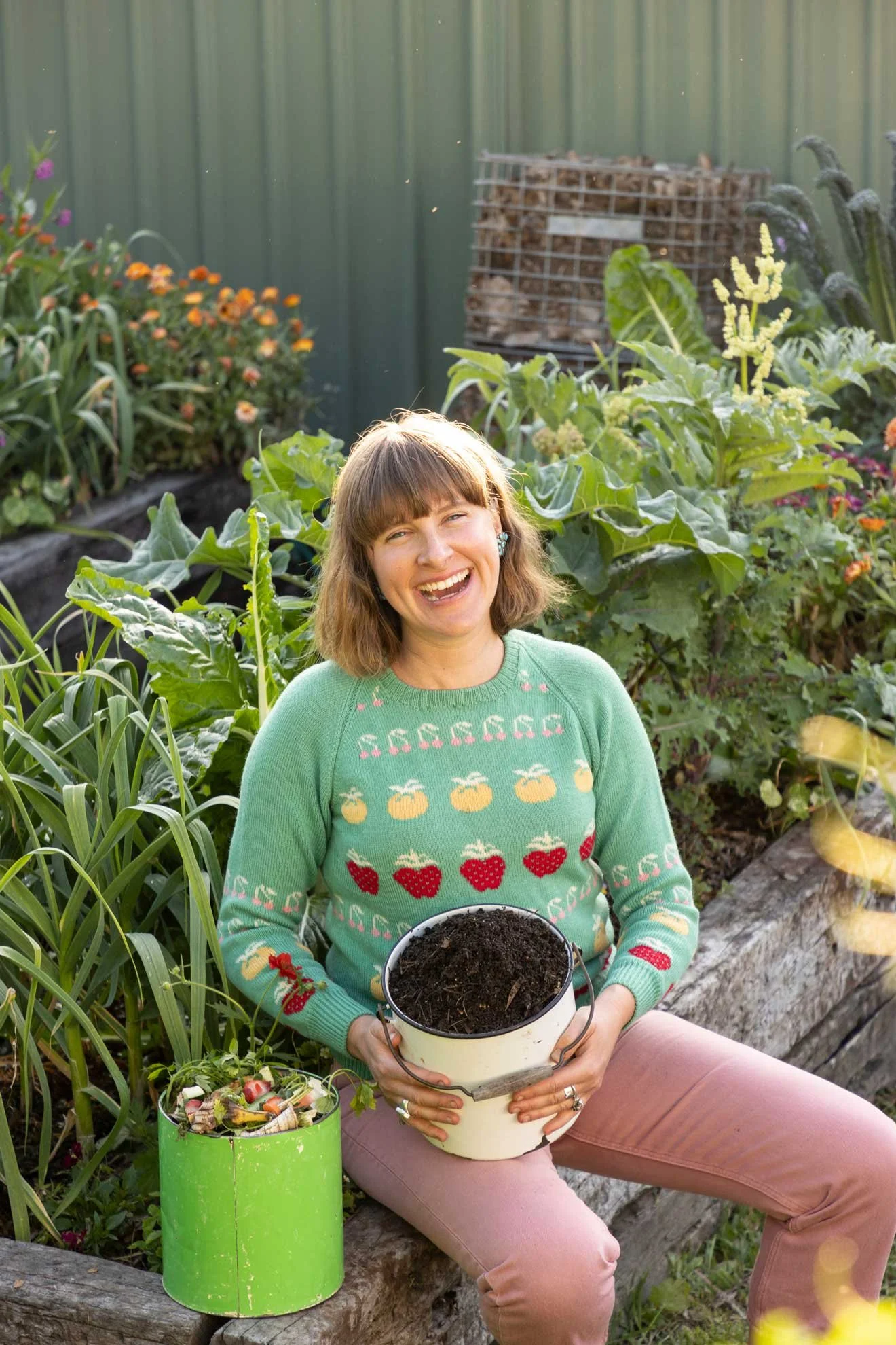 Photo of Compostable Kate holding a buck of fresh compost and green waste for 'The Compost Coach Book' photographed by Honey Atkinson