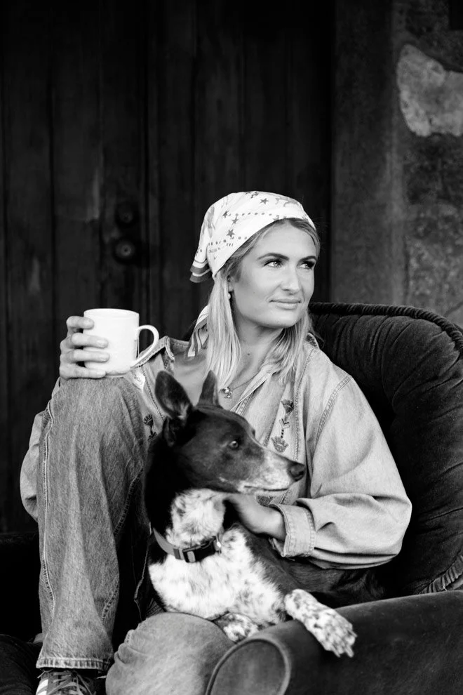 Black and white personal brand portrait, Gen of Reins to Resilience with her dog at stone cottage, Candelo Bega Valley NSW