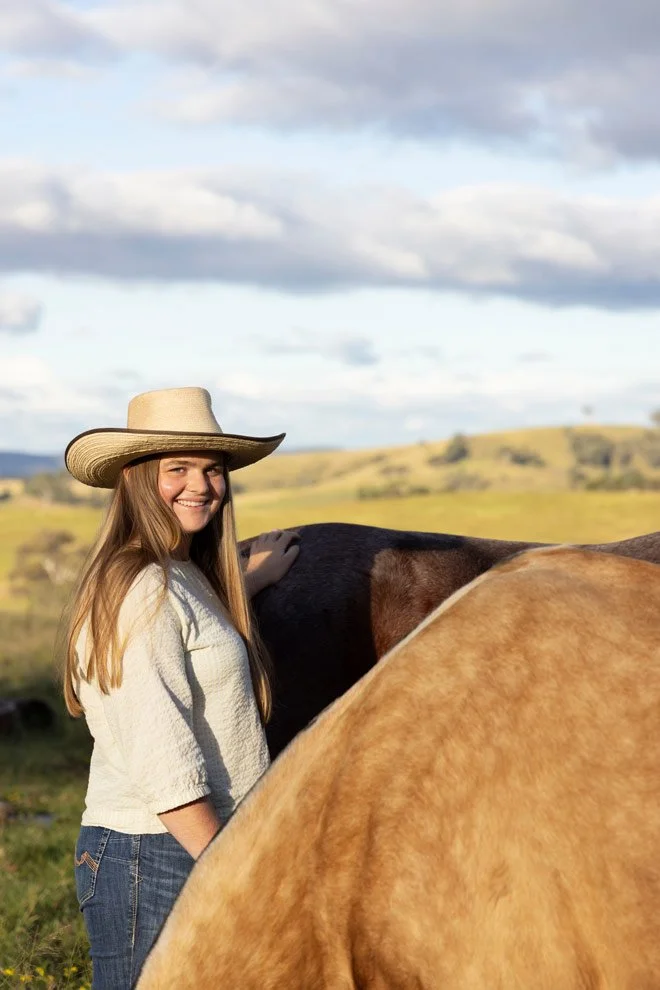 Brand photography Sapphire Coast, teenage participant smiling with horses at Reins to Resilience, Candelo Bega Valley NSW