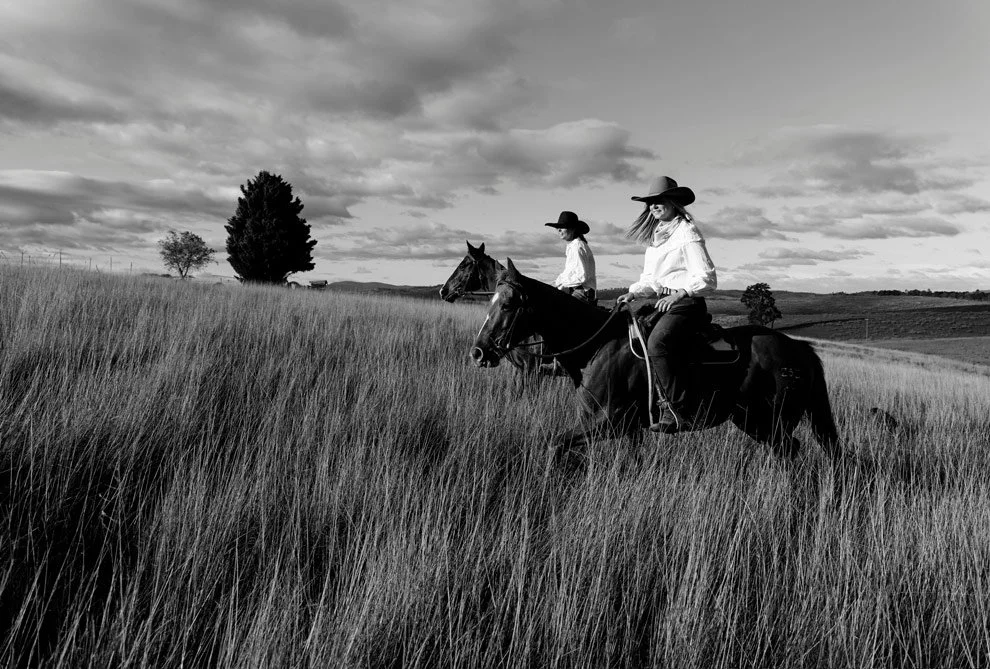 Black and white brand photography, Sarah and Gen of Reins to Resilience riding through long grass, Sapphire Coast NSW