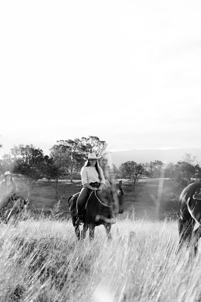 Black and white brand photography, rider on horseback through long grass at Reins to Resilience, Candelo Sapphire Coast NSW