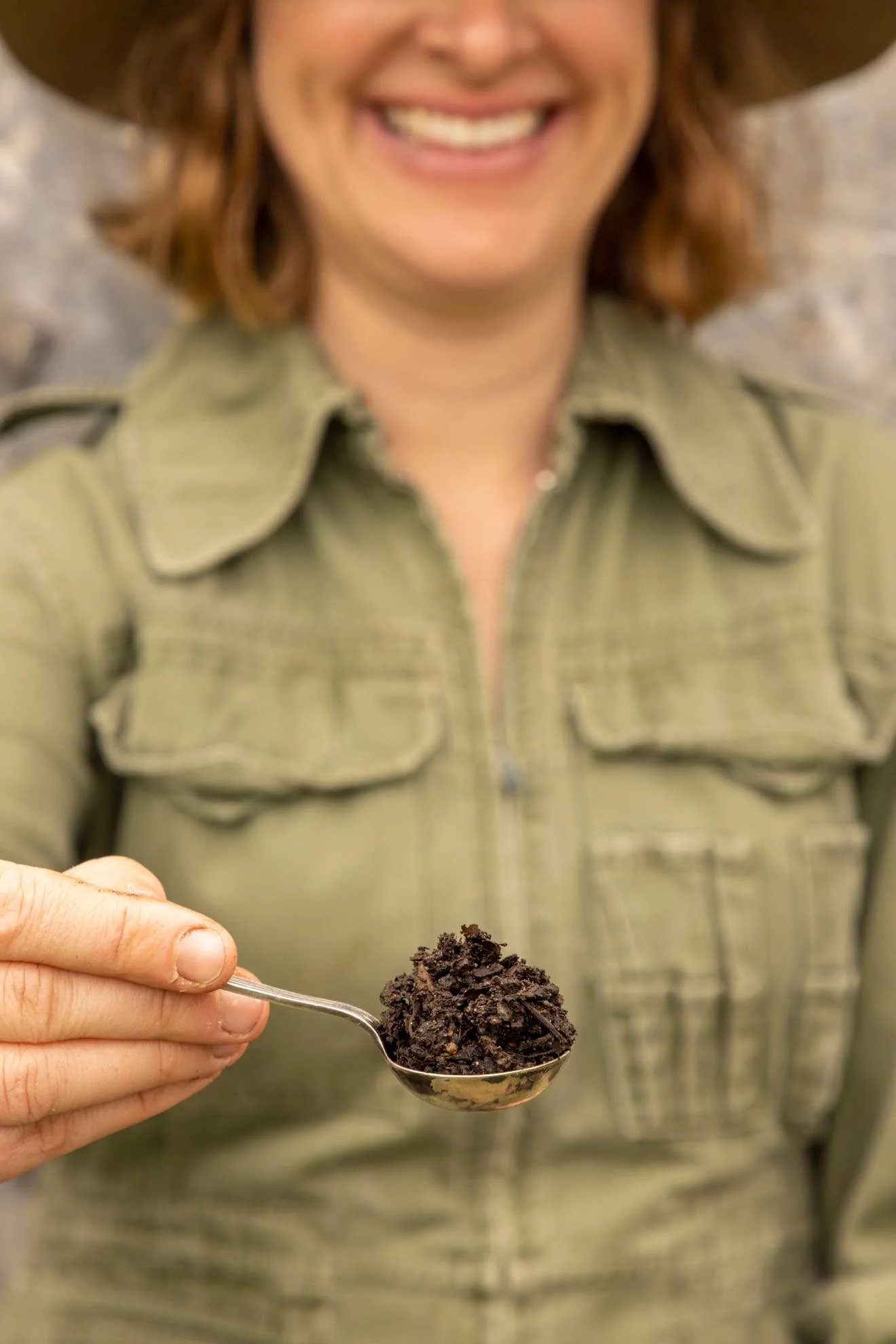 Photo of Composable Kate holding a spoonful of finished compost from 'Compost Coach Book' photographed by Honey Atkinson