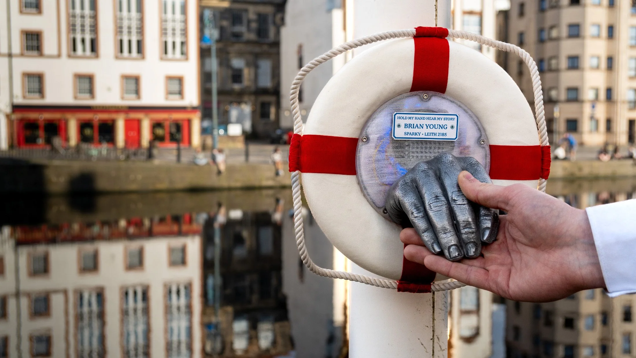 Brian Young, electrician from 2185, speaks through a Helping Hand on The Shore, turning touch into a future encounter.