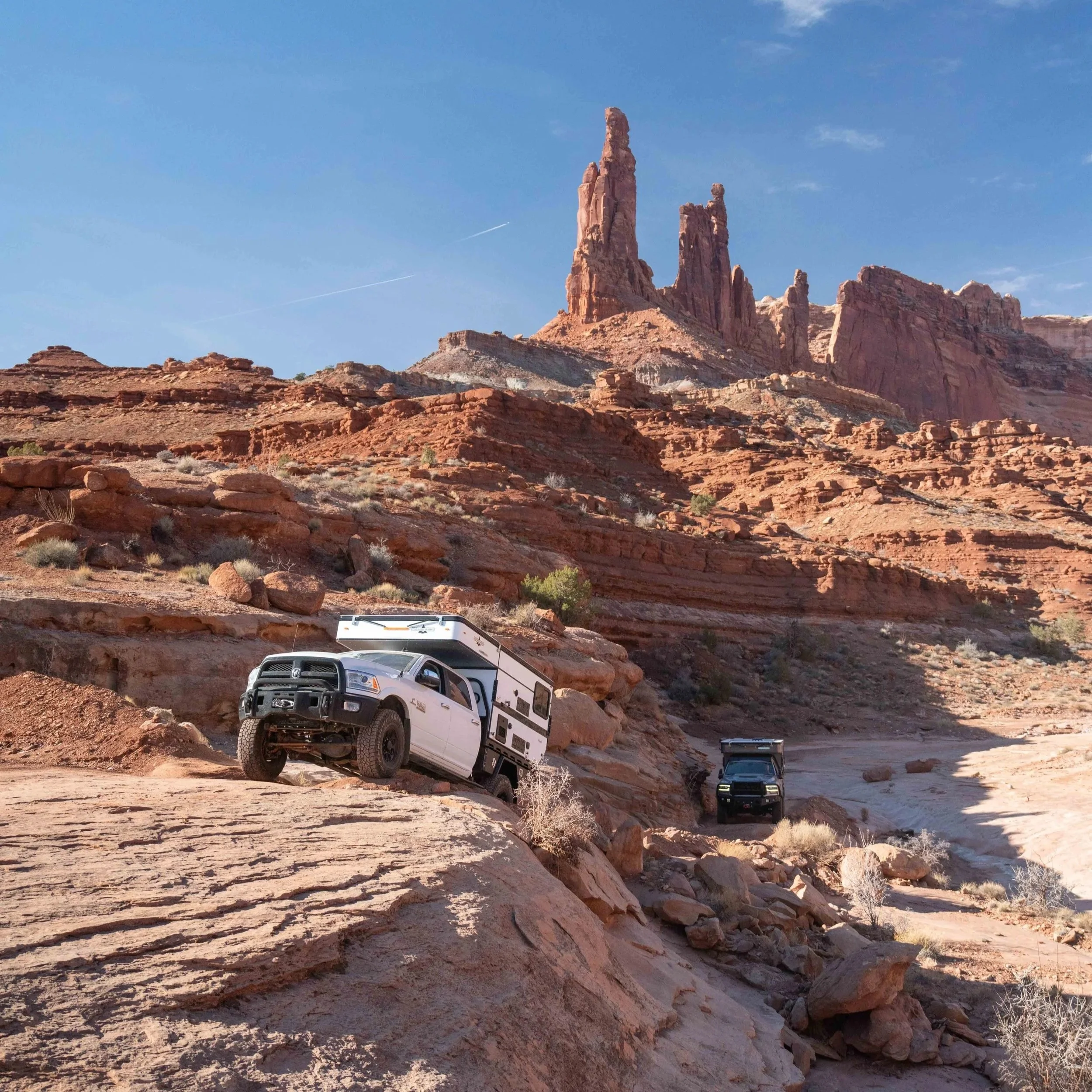Red rock formations in a desert landscape with a clear blue sky and a few scattered clouds.
