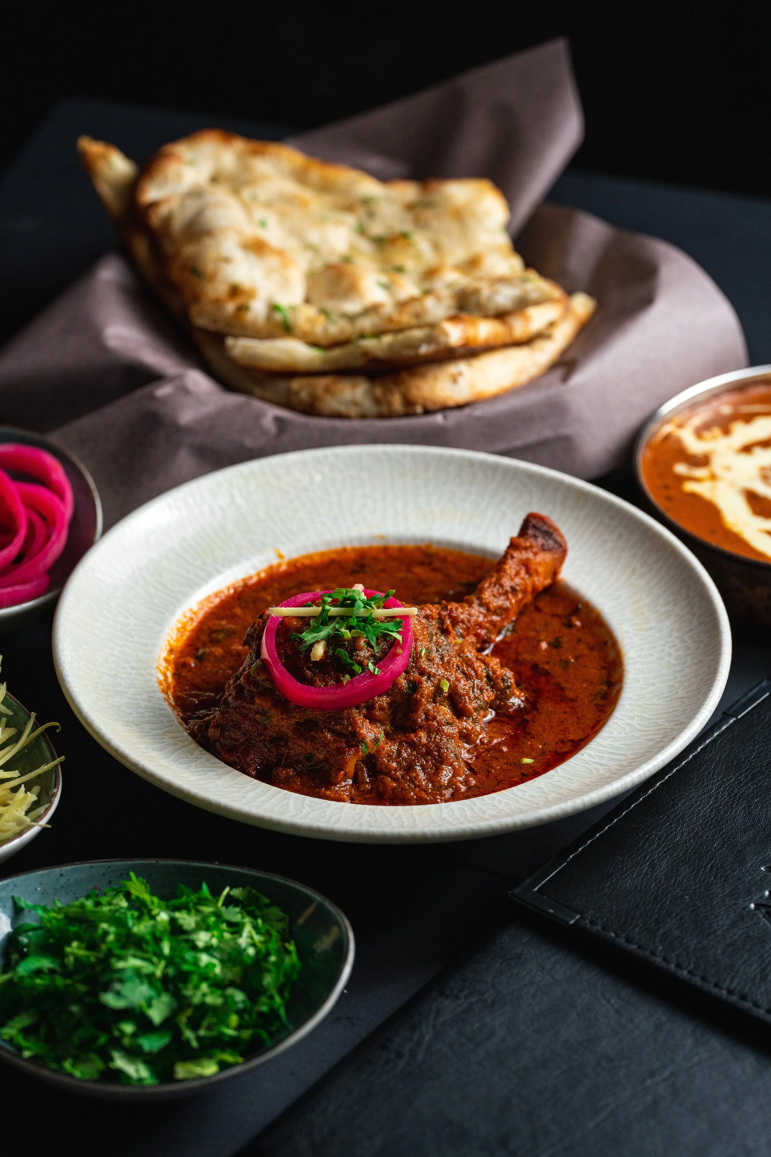 Braised Lamb Shank Masala, a prestigious dish. Our Chef's signature lamb dish, featuring a tender, slow-braised lamb shank cooked in an aromatic curry. 