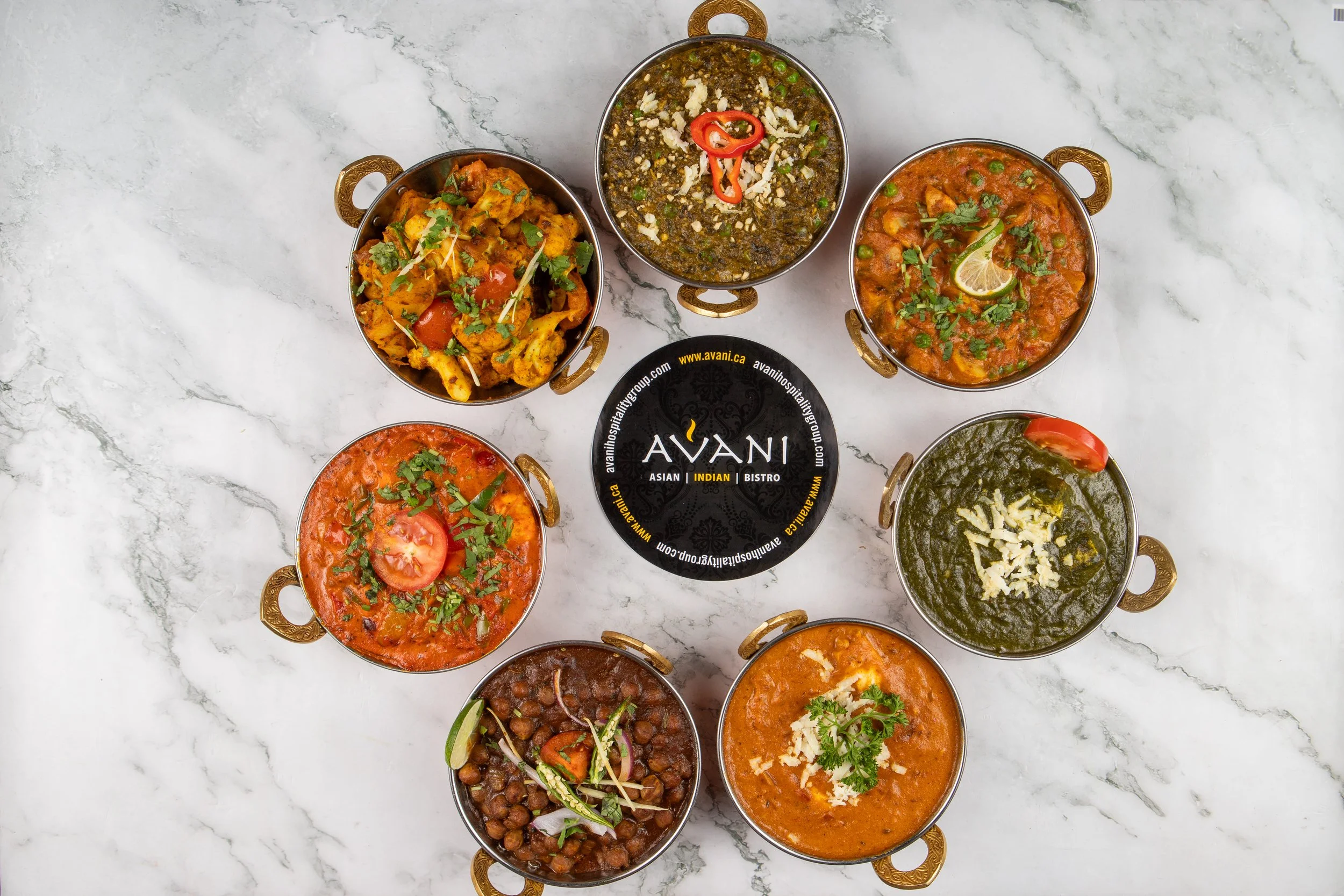 A vibrant selection of authentic Indian curries, beautifully arranged and served in traditional brass . Rich colors, fresh garnishes, and bold flavors come together to showcase the essence of Indian cuisine.