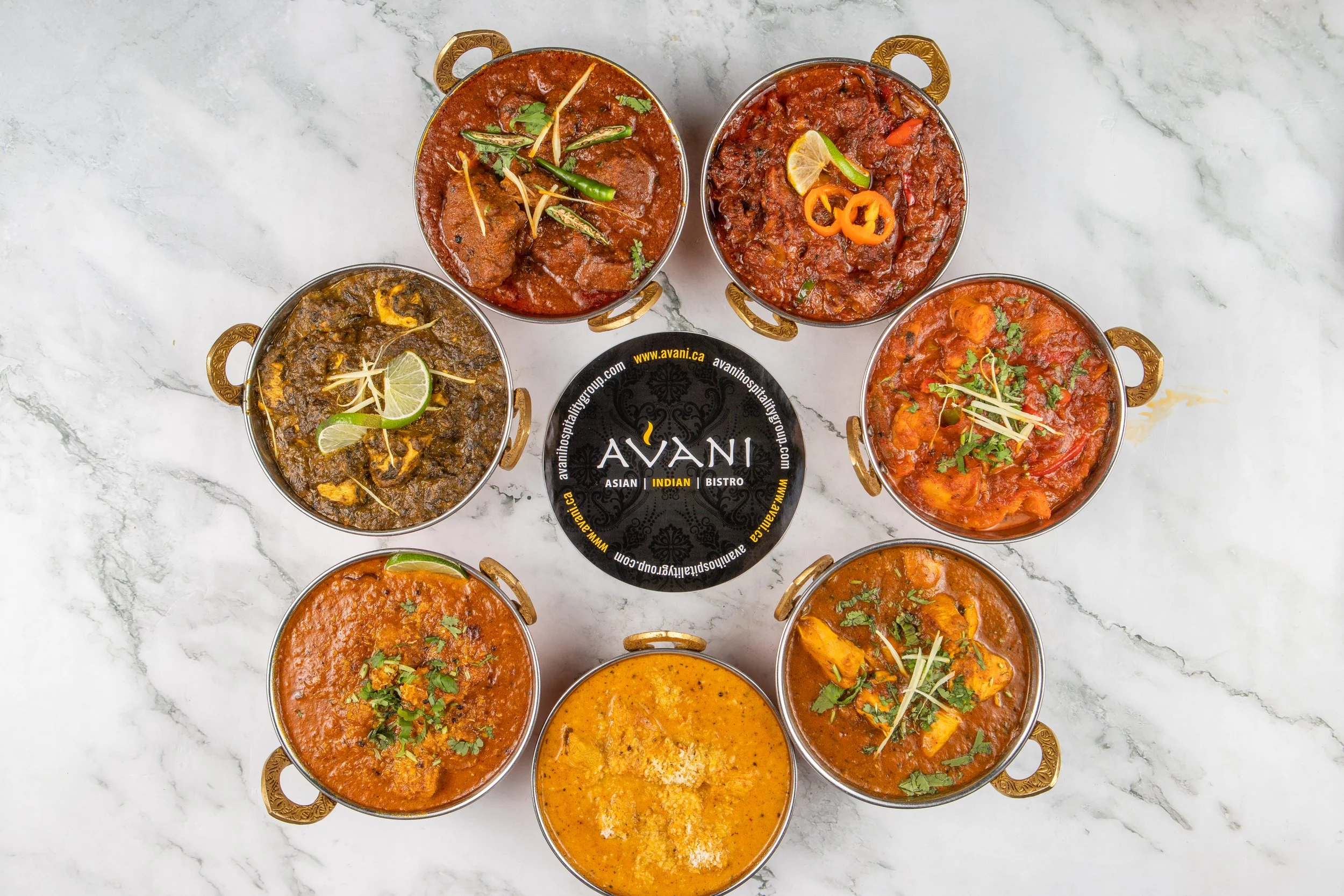 A vibrant selection of authentic Indian curries, beautifully arranged and served in traditional brass . Rich colors, fresh garnishes, and bold flavors come together to showcase the essence of Indian cuisine.