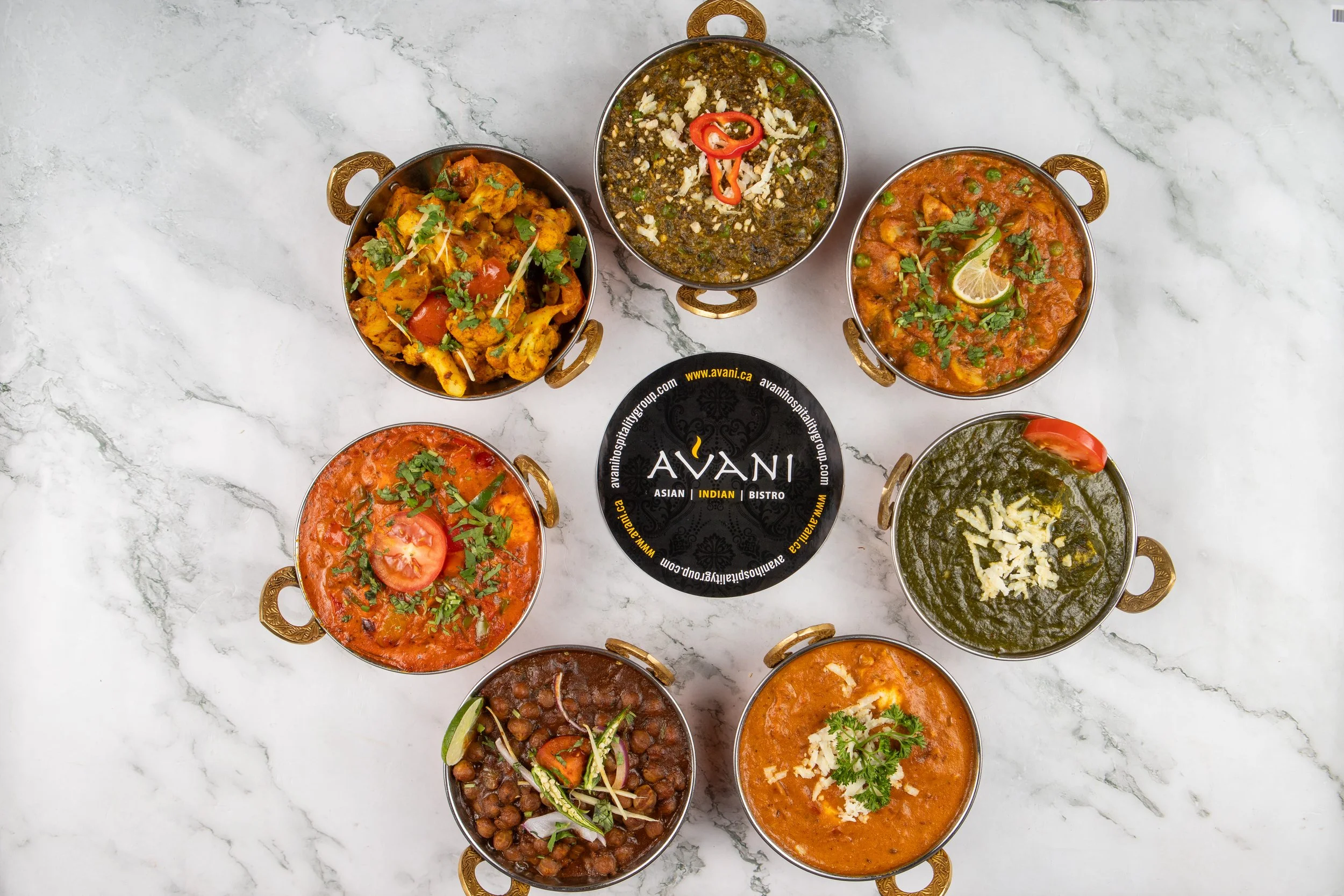 A vibrant selection of authentic Indian curries, beautifully arranged and served in traditional brass . Rich colors, fresh garnishes, and bold flavors come together to showcase the essence of Indian cuisine.
